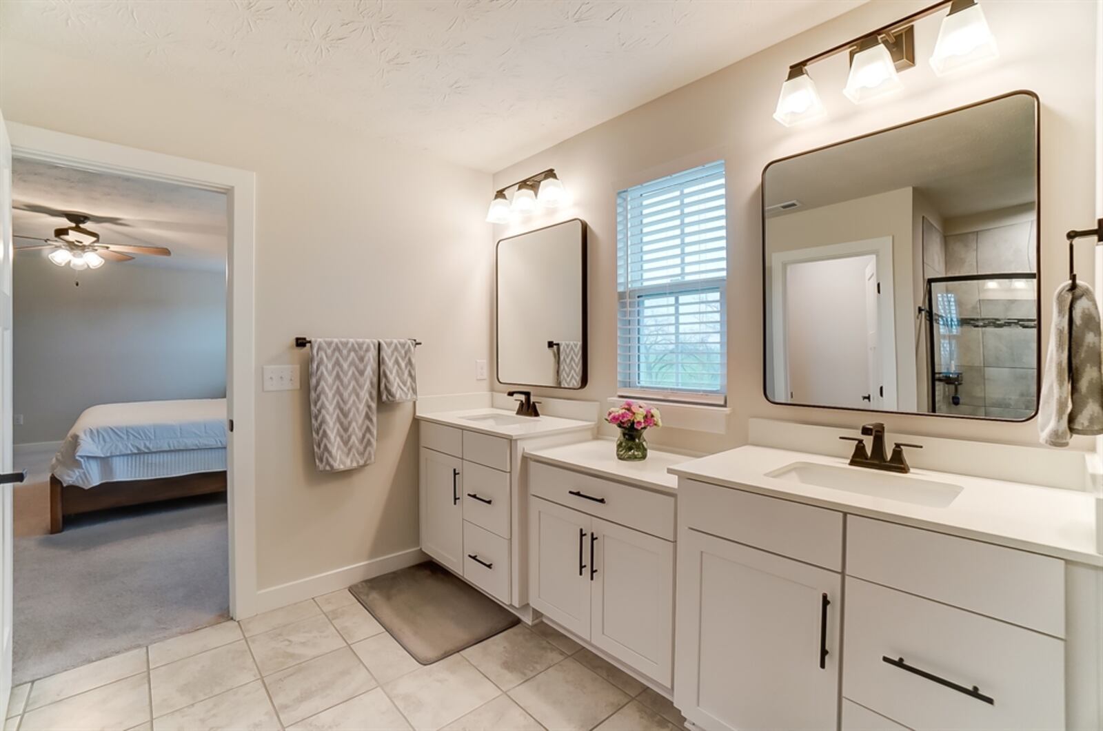 The bath has two elevated vanities with single sinks and a storage cabinet. 