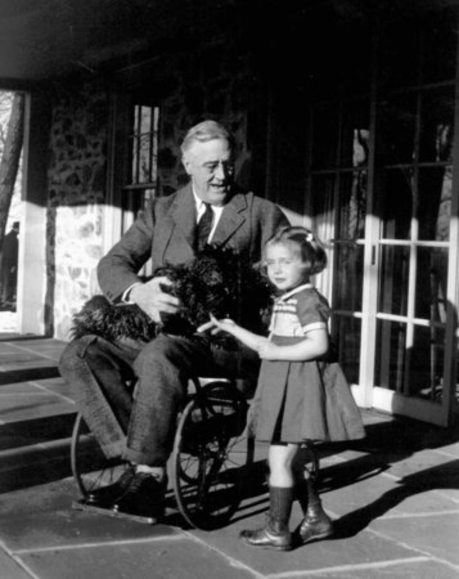 A wheelchair-bound President Franklin Roosevelt holds his black Scottie Fala while talking to Ruthie Bie, granddaughter of the caretakers of the Hill Top Cottage at his Hyde Park, N.Y. home in Feb. 1941.