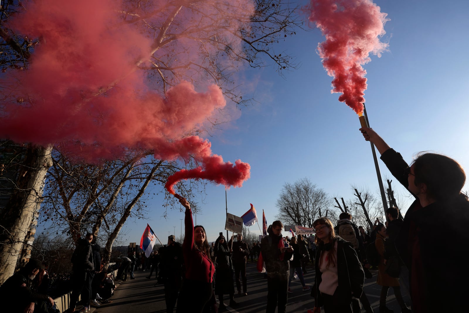 People light up smoke flares as they march during a protest over the collapse of a concrete canopy that killed 15 people more than two months ago, in Novi Sad, Serbia, Saturday, Feb. 1, 2025. (AP Photo/Darko Vojinovic)