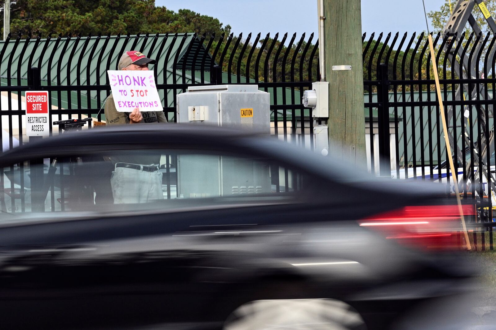 A protestor holds up a sign as traffic bypasses prior to the scheduled execution of Richard Moore, Friday, Nov. 1, 2024, outside of Broad River Correctional Institution in Columbia, S.C. (AP Photo/Matt Kelley)