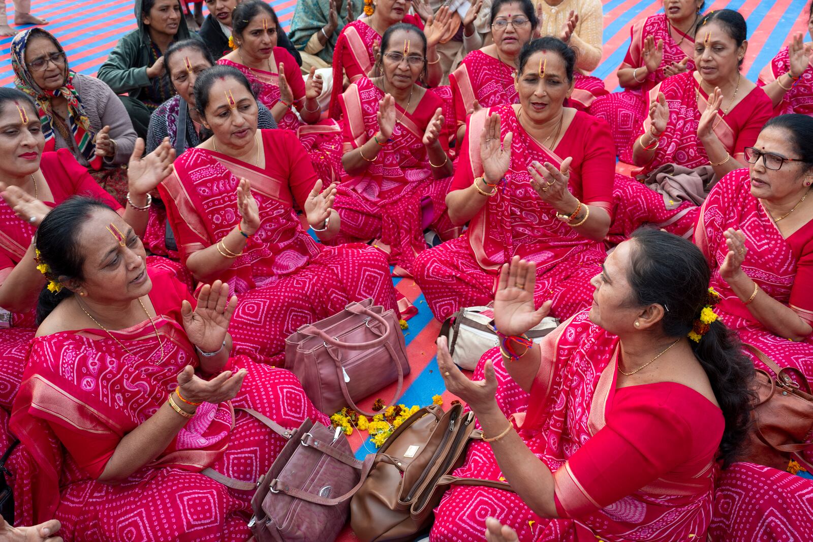 Hindu women devotees sing hymns as they gather at the confluence of the Ganges, the Yamuna and the mythical Saraswati rivers, a day before the official beginning of the 45-day-long Maha Kumbh festival, in Prayagraj, India, Sunday, Jan. 12, 2025. (AP Photo/Ashwini Bhatia)