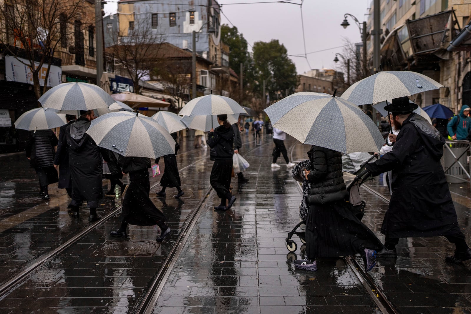 People walk with umbrellas on a rainy day in Jerusalem, Israel, Friday, Dec. 20, 2024. (AP Photo/Ohad Zwigenberg)