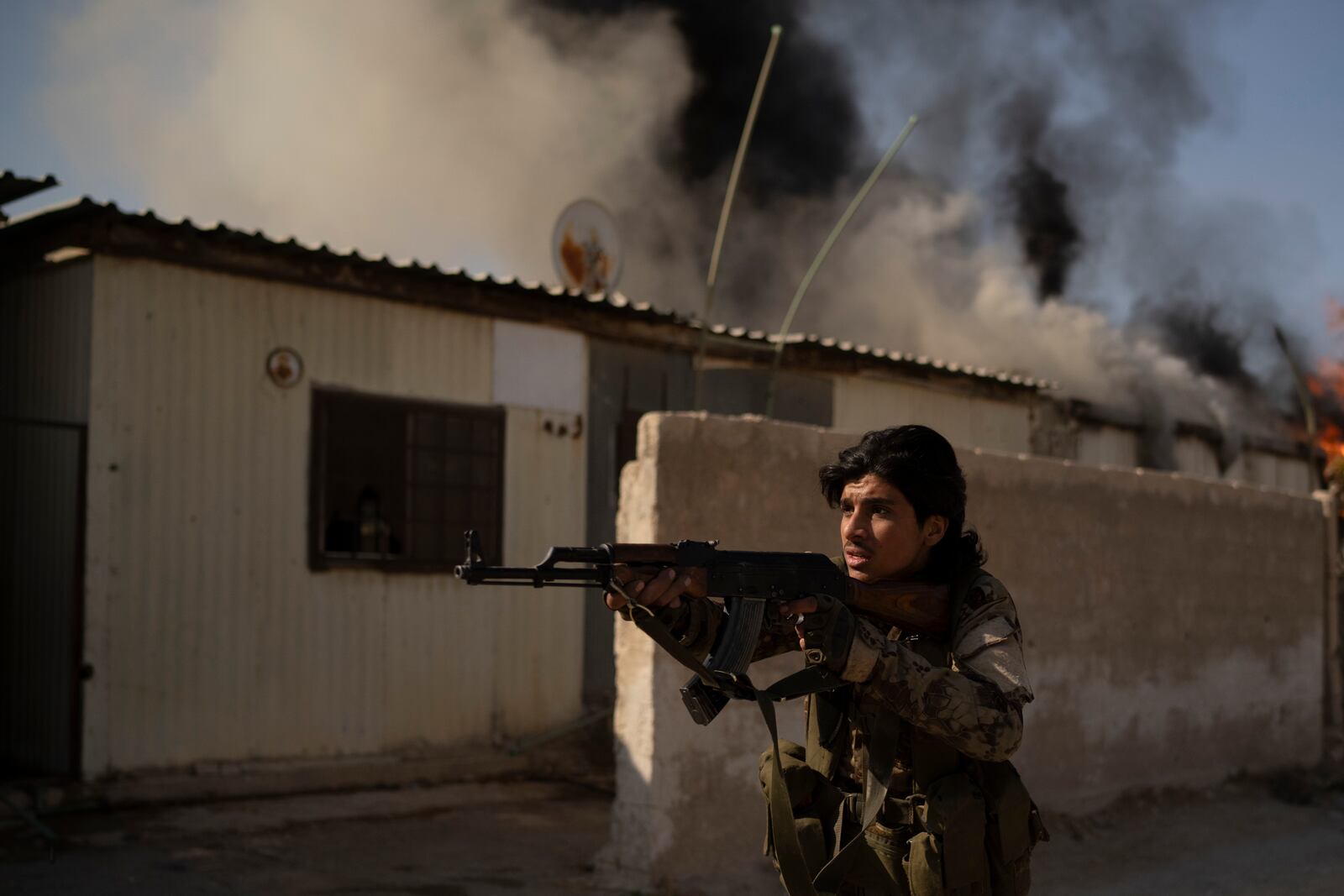 A Syrian fighter aims his weapon in direction of suspected looters at a residential complex of former Bashar Assad's military officers at the village of Husseiniyeh, in the outskirts of Damascus, Syria, Sunday, Dec. 15, 2024. (AP Photo/Leo Correa)