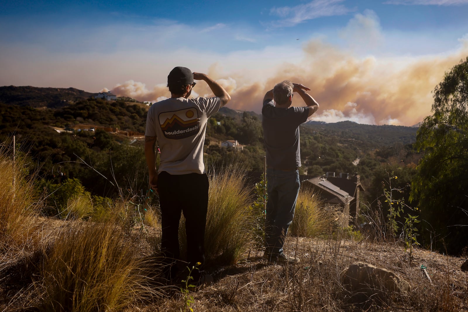 Topanga Canyon inhabitants look on as the Palisades Fire burns in the hills between Pacific Palisades and Malibu Wednesday, Jan. 8, 2025 in Topanga, Calif. (AP Photo/Etienne Laurent)