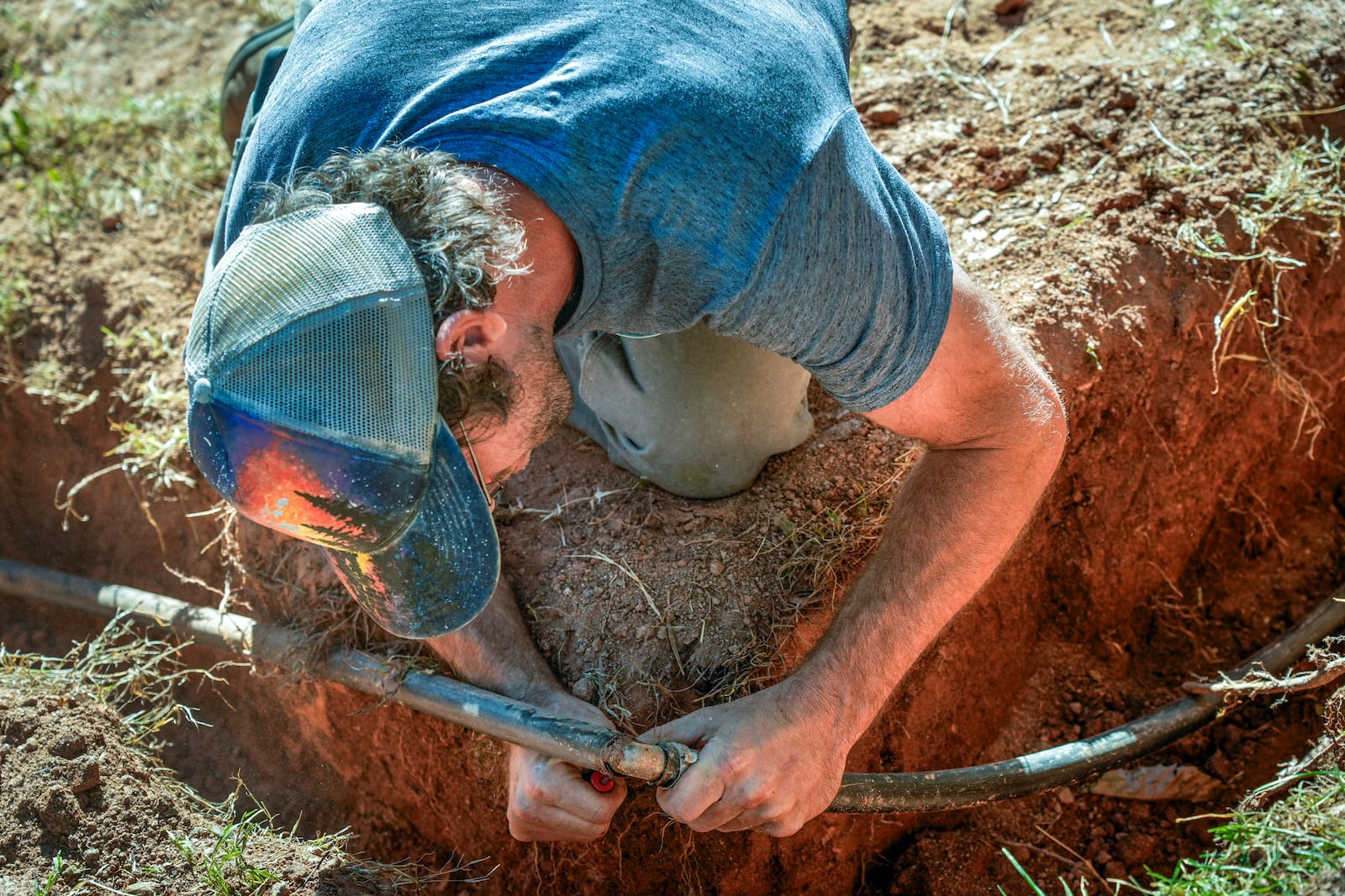 Jeffrey Martyn, a plumber and electrician works on a pipe fitting that draws water from a community well located on an urban farm that belongs to Bountiful Cities, a nonprofit organization, Monday, Oct. 14, 2024, in Asheville, N.C. (AP Photo/Kathy Kmonicek)