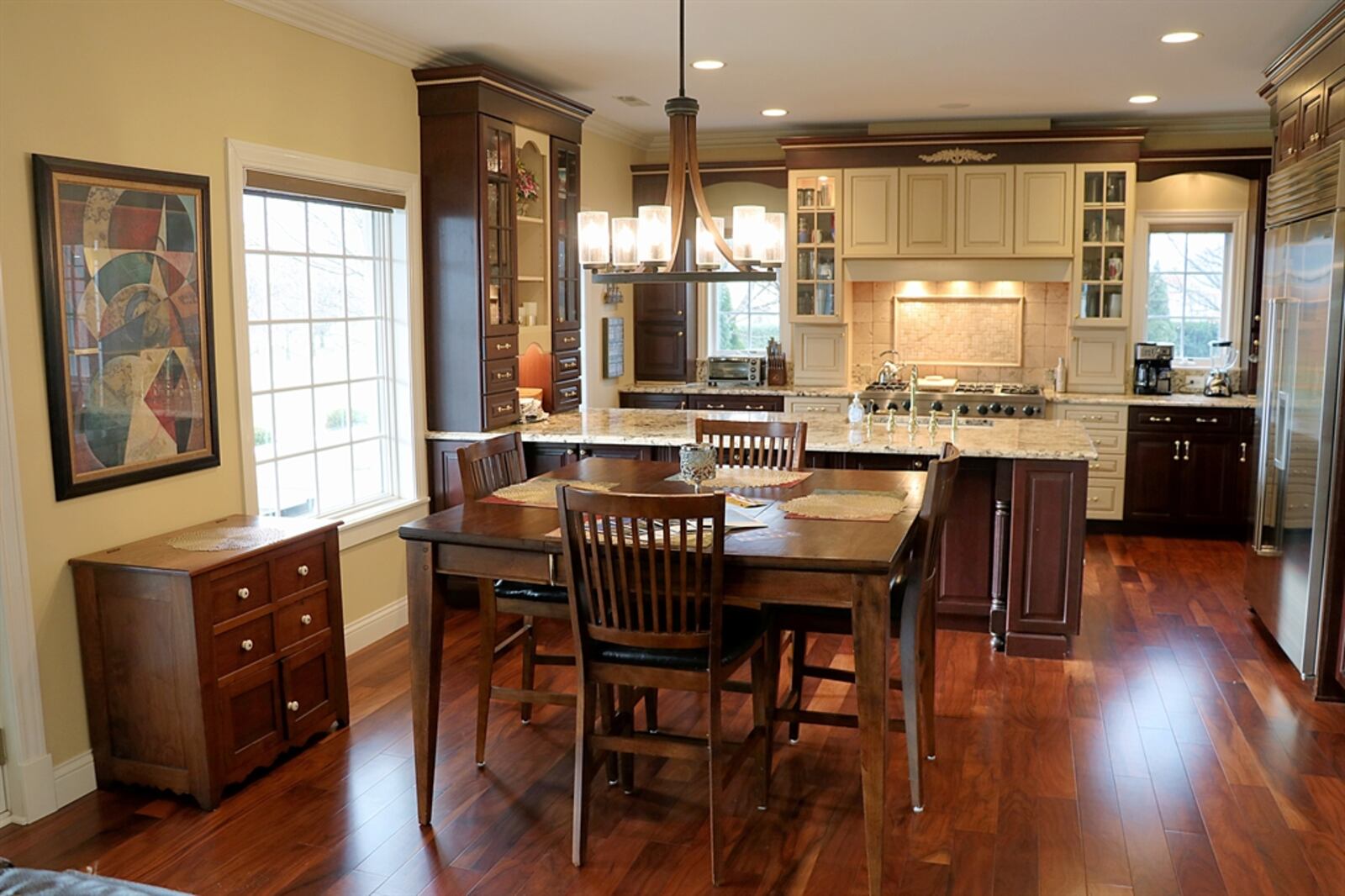 In the kitchen, a peninsula counter has an attached hutch with lighted glass shelves and spice drawers. The granite counter has a double sink and there are open shelves at the end. 