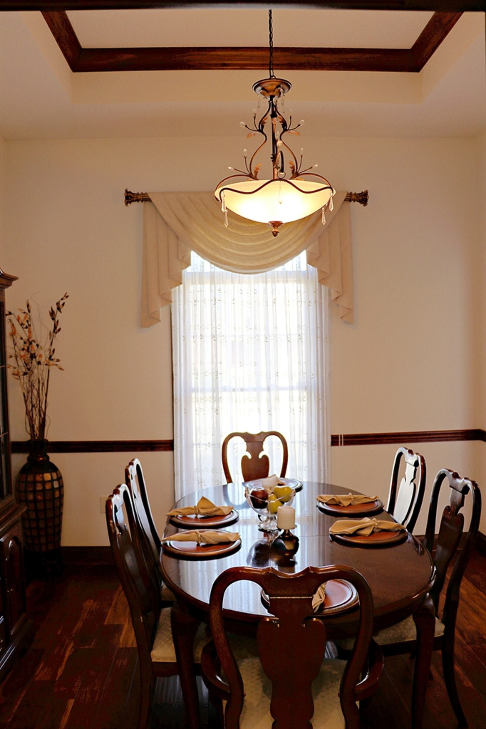 The dining room has a tray ceiling with a hanging light fixture and chair rail.