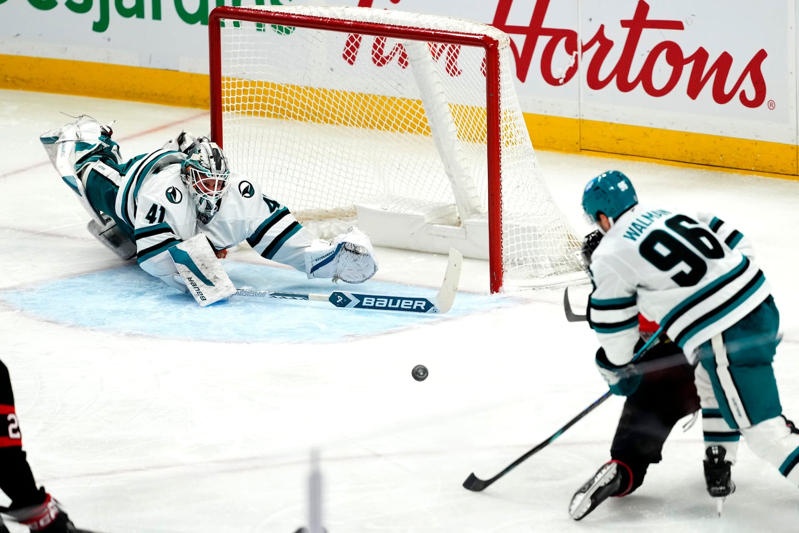 San Jose Sharks goaltender Vitek Vanecek (41) dives as he is scored on by Ottawa Senators' Tim Stutzle, bottom right, after getting caught out of his crease, during the third period of an NHL hockey game in Ottawa, Ontario, on Saturday, March 1, 2025. (Justin Tang/The Canadian Press via AP)