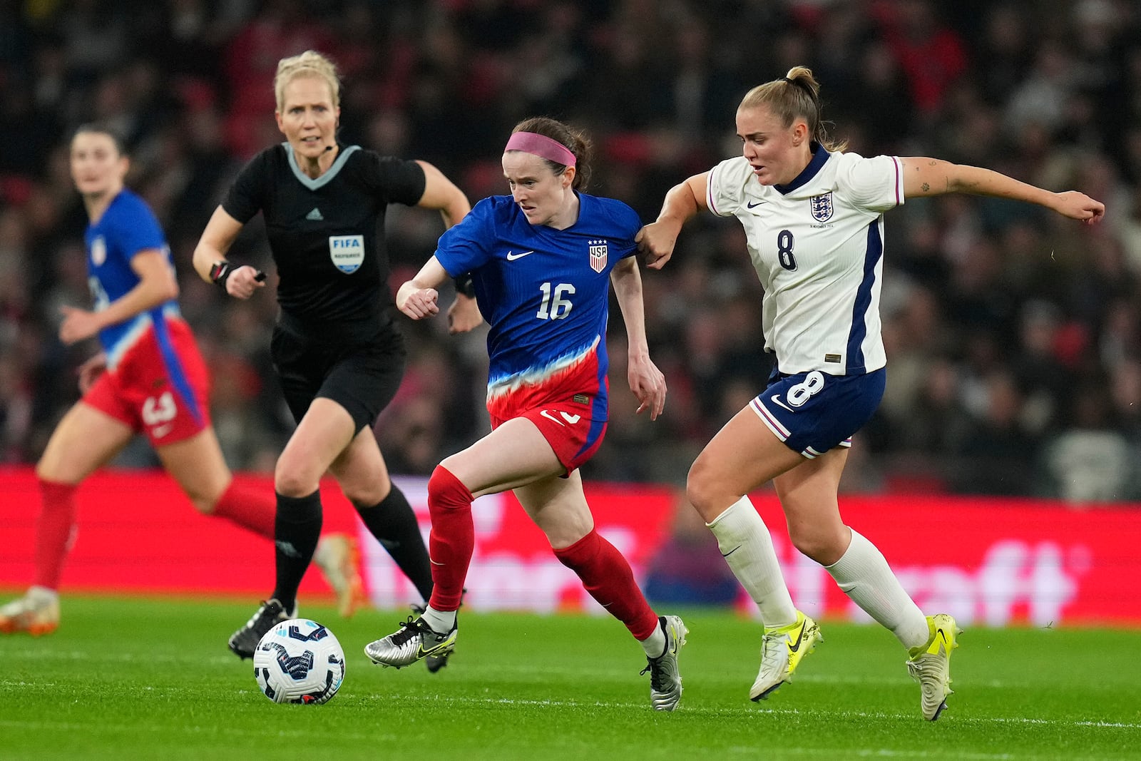 United States' Rose Lavelle and England's Georgia Stanwaychallenge for the ball whilst referee Lina Lehtovaara looks on during the International friendly women soccer match between England and United States at Wembley stadium in London, Saturday, Nov. 30, 2024. (AP Photo/Kirsty Wigglesworth)