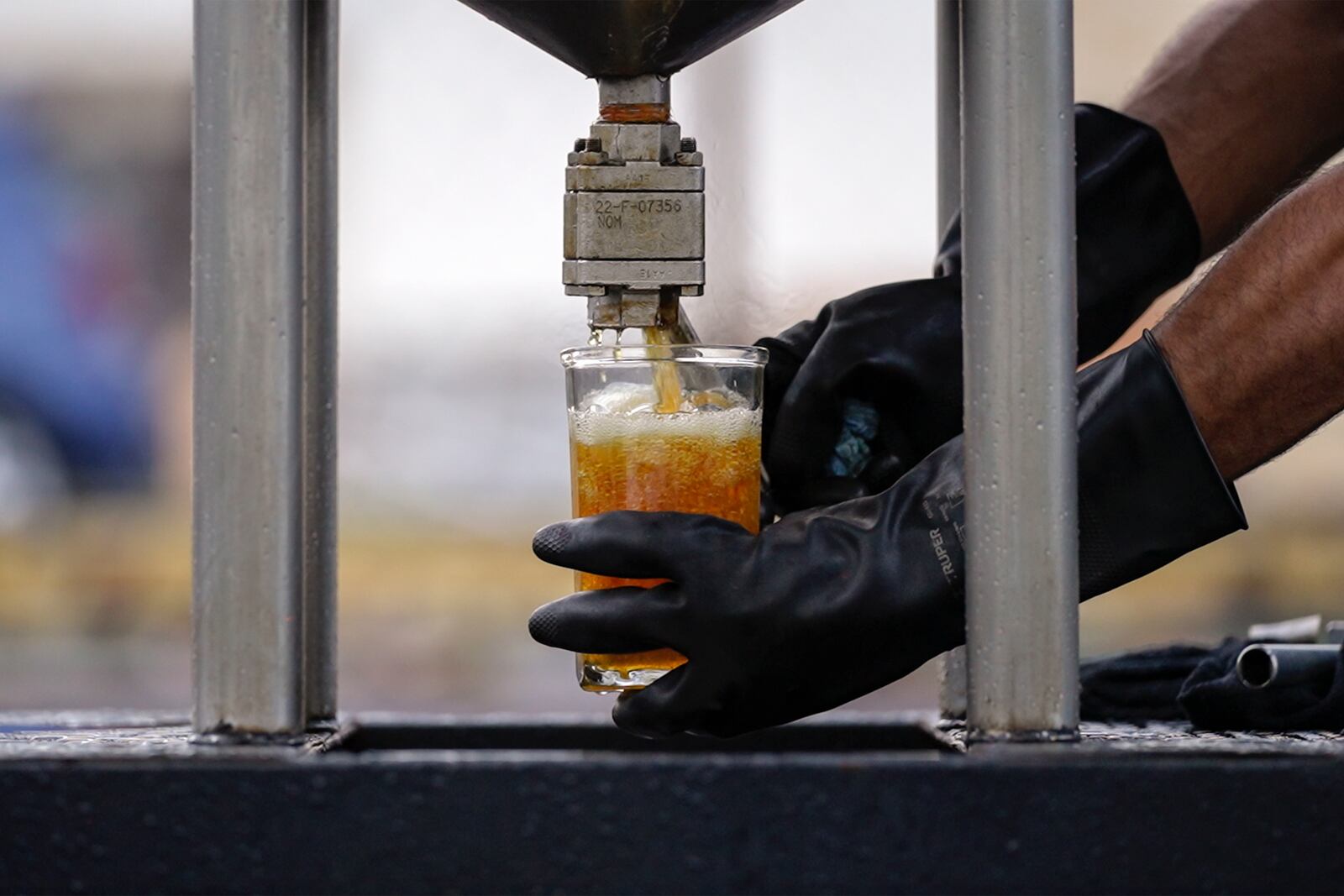 Carlos Parraguirre Diaz, head of technical operations at Petgas, obtains fuel during a demonstration operation of Petgaserita, a non-catalytic pyrolysis machine that converts plastic into fuel, n Boca del Rio, Veracruz, Mexico, Jan. 4, 2025. (AP Photo/Felix Marquez)