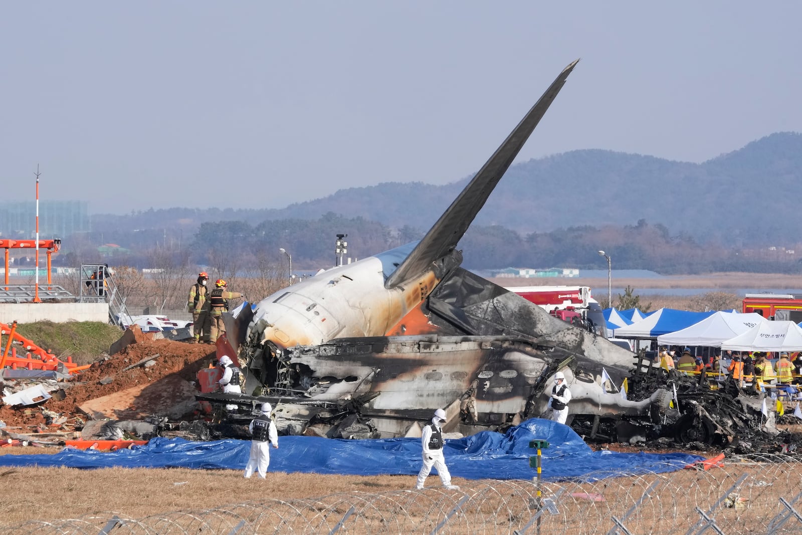 Firefighters and rescue team members work near the wreckage of a passenger plane at Muan International Airport in Muan, South Korea, Sunday, Dec. 29, 2024. (AP Photo/Ahn Young-joon)