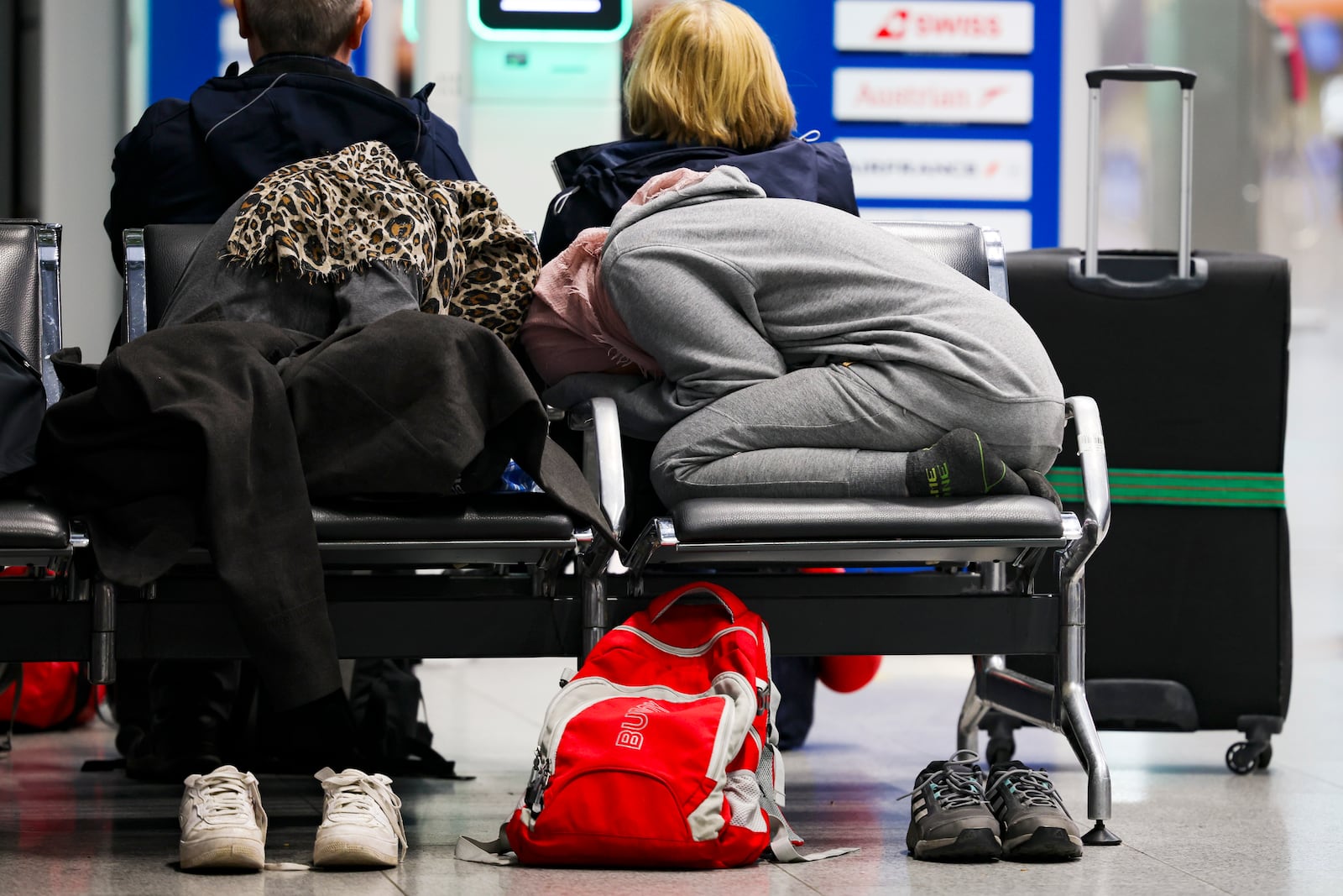 Travelers rest on a bench in the departure terminal at Dusseldorf Airport, Germany Monday, March 10, 2025. (Christoph Reichwein/dpa via AP)