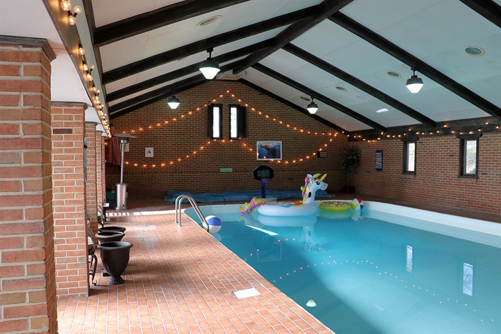 The pool house has a cathedral ceiling and five sets of double patio doors that open out to the courtyard. Paver bricks surround the in-ground saltwater heated pool.