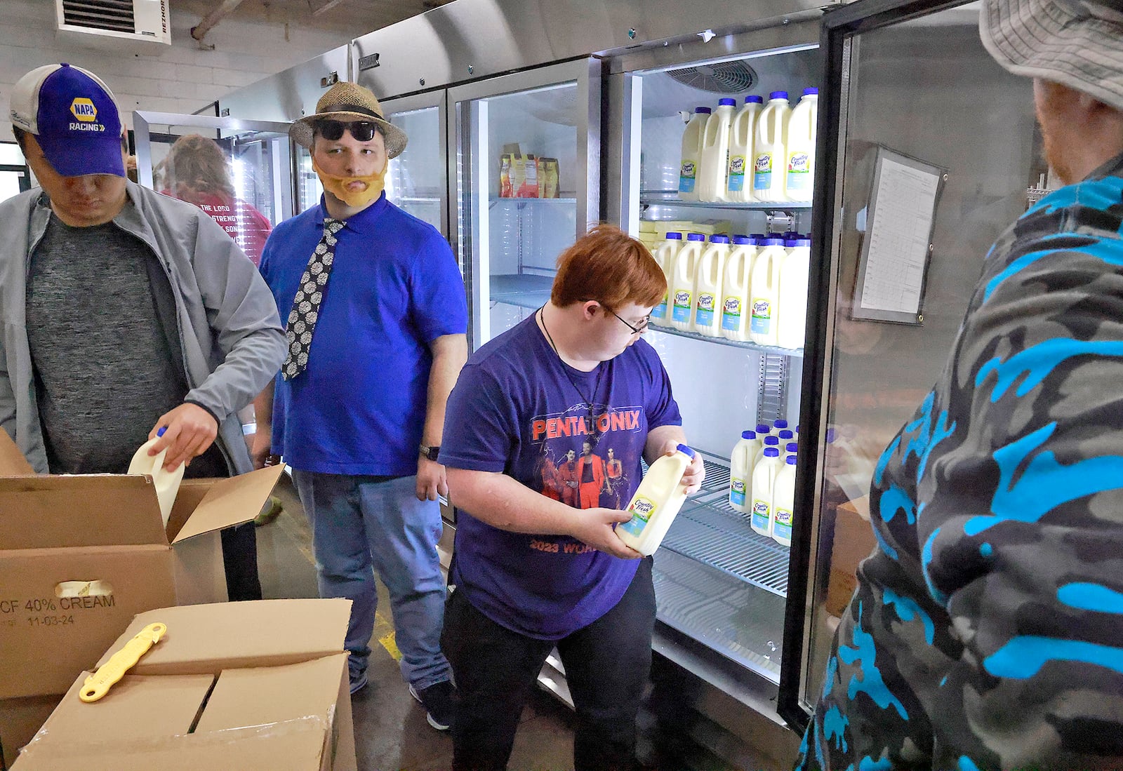 Volunteers from the Downsize Farms, in Urbana, stock the coolers at Second Harvest Food Bank with milk Monday, Nov. 4, 2024. BILL LACKEY/STAFF