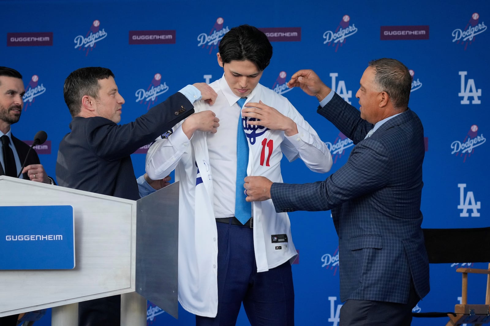 FILE - Japanese right-hander pitcher Roki Sasaki, 23, is helped with his #11 Los Angeles Dodgers jersey as he is introduced during a news conference at Dodger Stadium in Los Angeles, Jan. 22, 2025. (AP Photo/Damian Dovarganes, File)