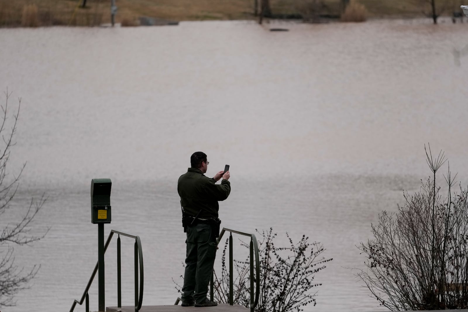 A park ranger takes picture of flood water at Dunbar Cave State Park, Sunday, Feb. 16, 2025, in Clarksville, Tenn. (AP Photo/George Walker IV)