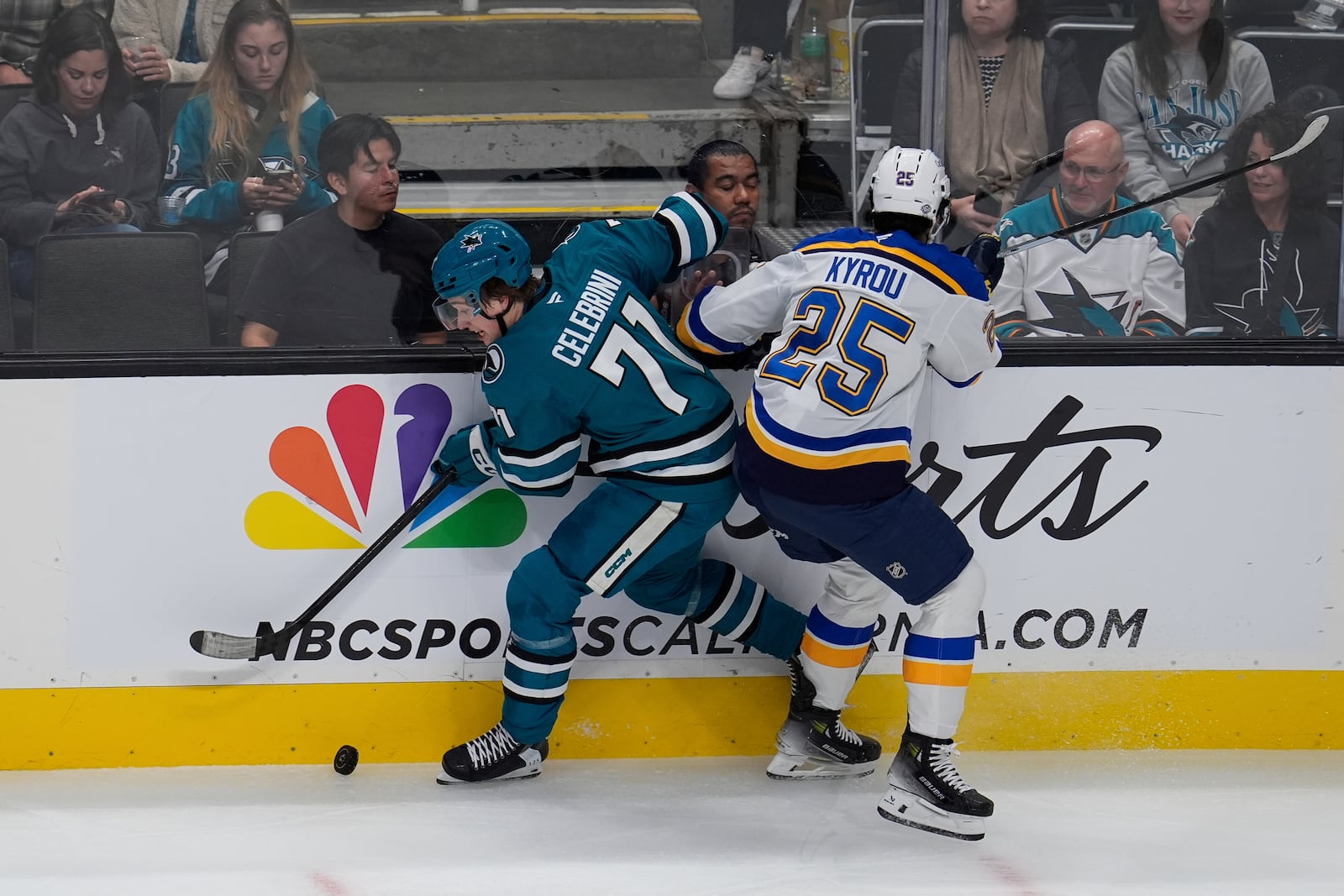 San Jose Sharks center Macklin Celebrini, left, and St. Louis Blues center Jordan Kyrou (25) complete for possession of the puck during the first period of an NHL hockey game Thursday, Oct. 10, 2024, in San Jose, Calif. (AP Photo/Godofredo A. Vásquez)