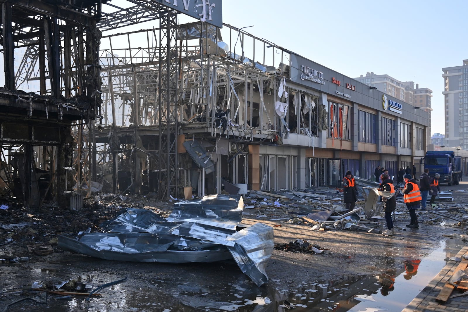 Municipal workers clean up after Russian drones hit shops during the night attack in Odesa, Ukraine, Friday, March 21, 2025. (AP Photo/Michael Shtekel)