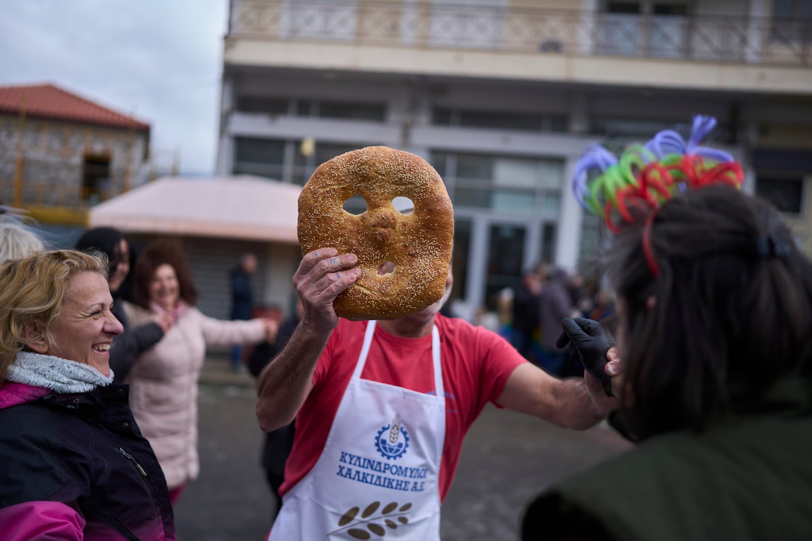 A baker holds up a mask-shaped loaf during carnival celebrations in Distomo, a village in central Greece, on Monday, March 3, 2025. (AP Photo/Petros Giannakouris)