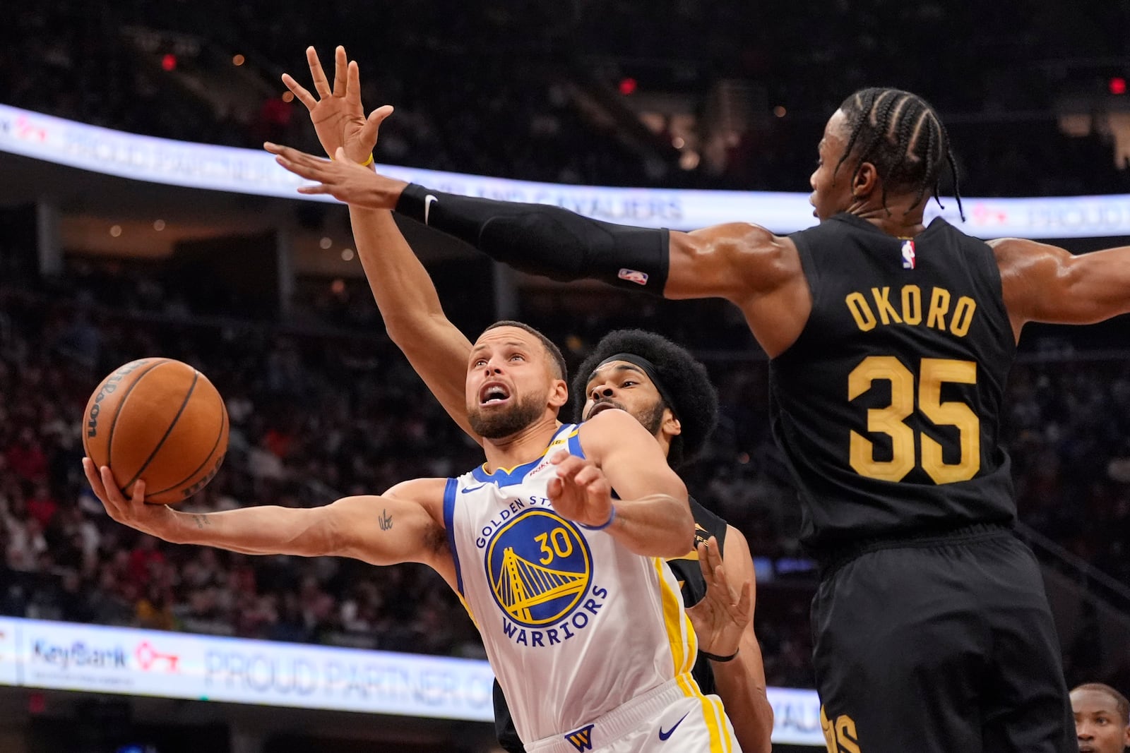 Golden State Warriors guard Stephen Curry (30) goes to the basket in front of Cleveland Cavaliers center Jarrett Allen, rear, and forward Isaac Okoro (35) in the first half of an NBA basketball game, Friday, Nov. 8, 2024, in Cleveland. (AP Photo/Sue Ogrocki)