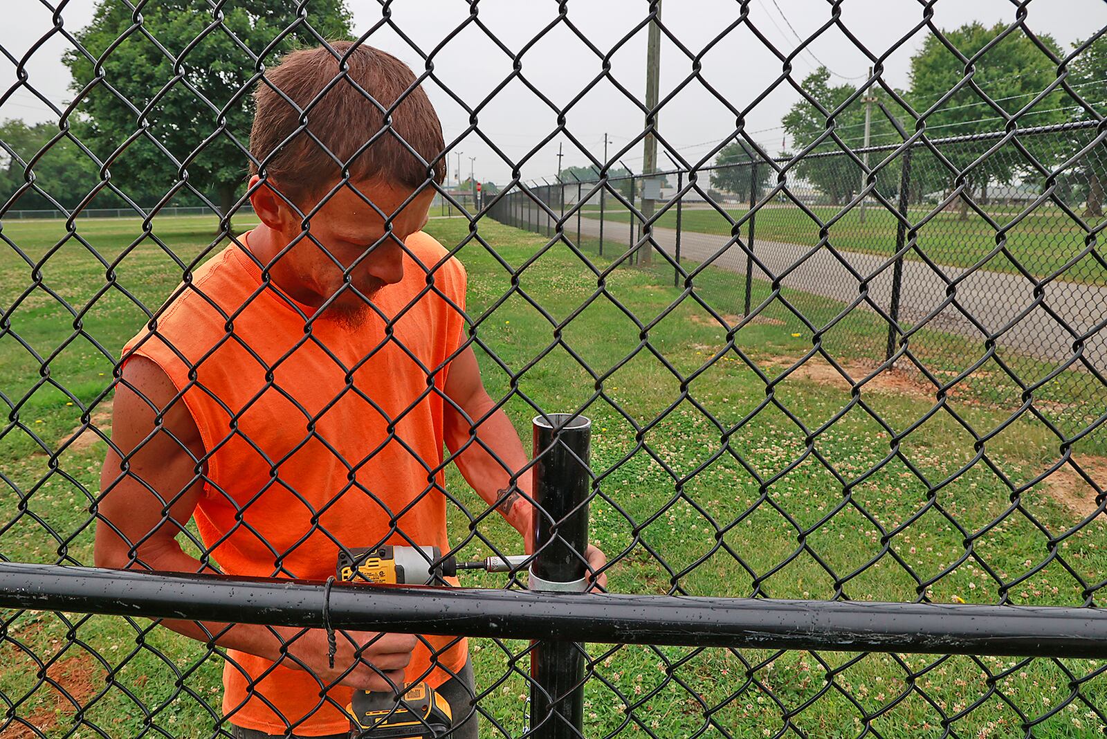 Preston Lookabaugh, from the Springfield Fence Company, works on the new fence at the Clark County Fairgrounds Monday, June 20, 2023. The new fence separates the new general admission parking area from the rest of the fairgrounds. Fairgoers will park their car and walk through a gate where they will pay admission. BILL LACKEY/STAFF