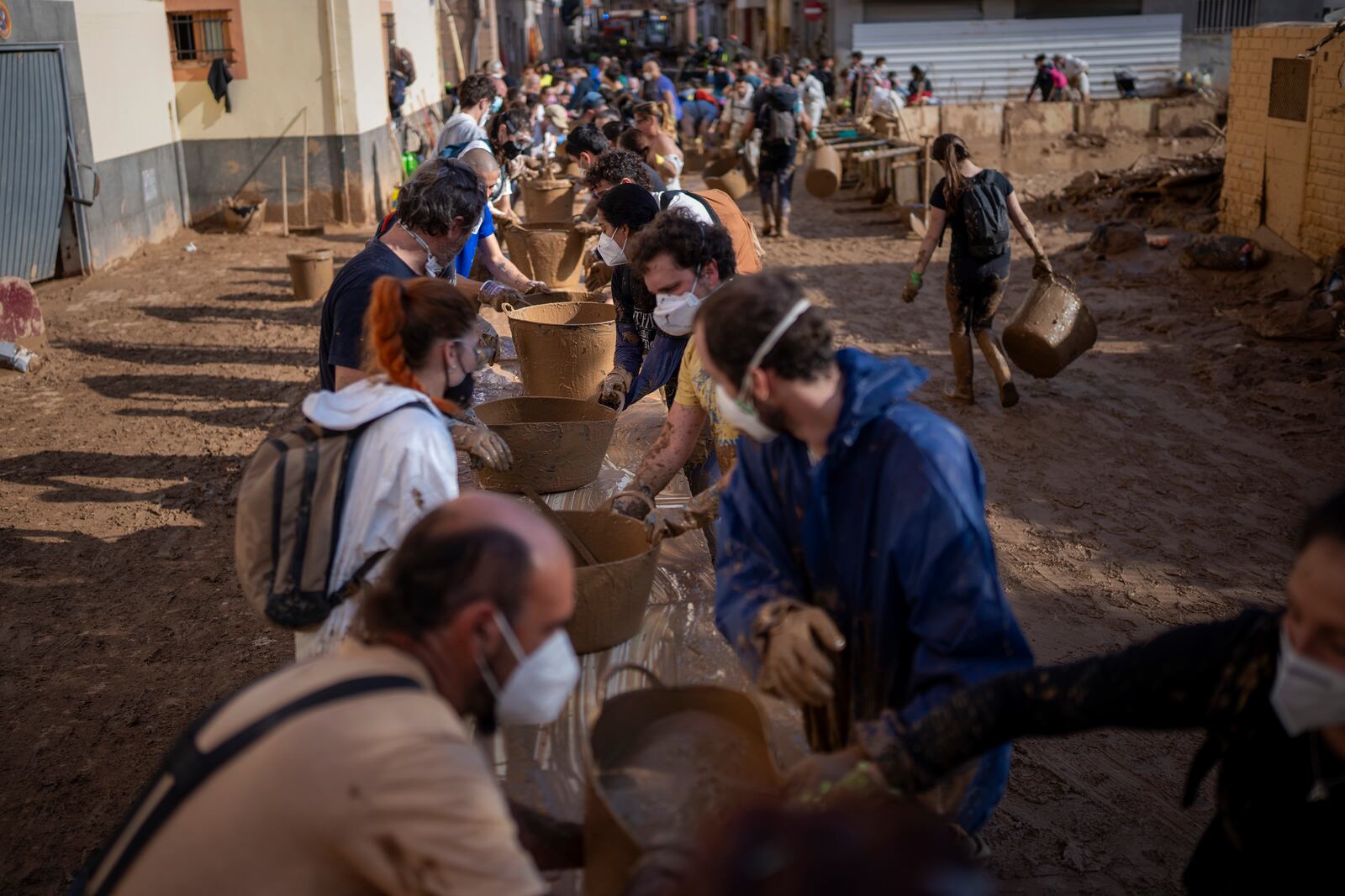 Volunteers make a human chain to evacuate the mud in buckets in an area still flooded with mud in Masanasa, Valencia, Spain, Thursday, Nov. 7, 2024. (AP Photo/Emilio Morenatti)