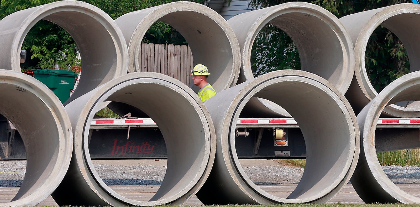 A construction worker walks past a row of concrete colverts as he prepares to unload more from a flatbed semi trailer on Enon-Xenia Road in front of Greenon School Wednesday, June 7, 2023. BILL LACKEY/STAFF