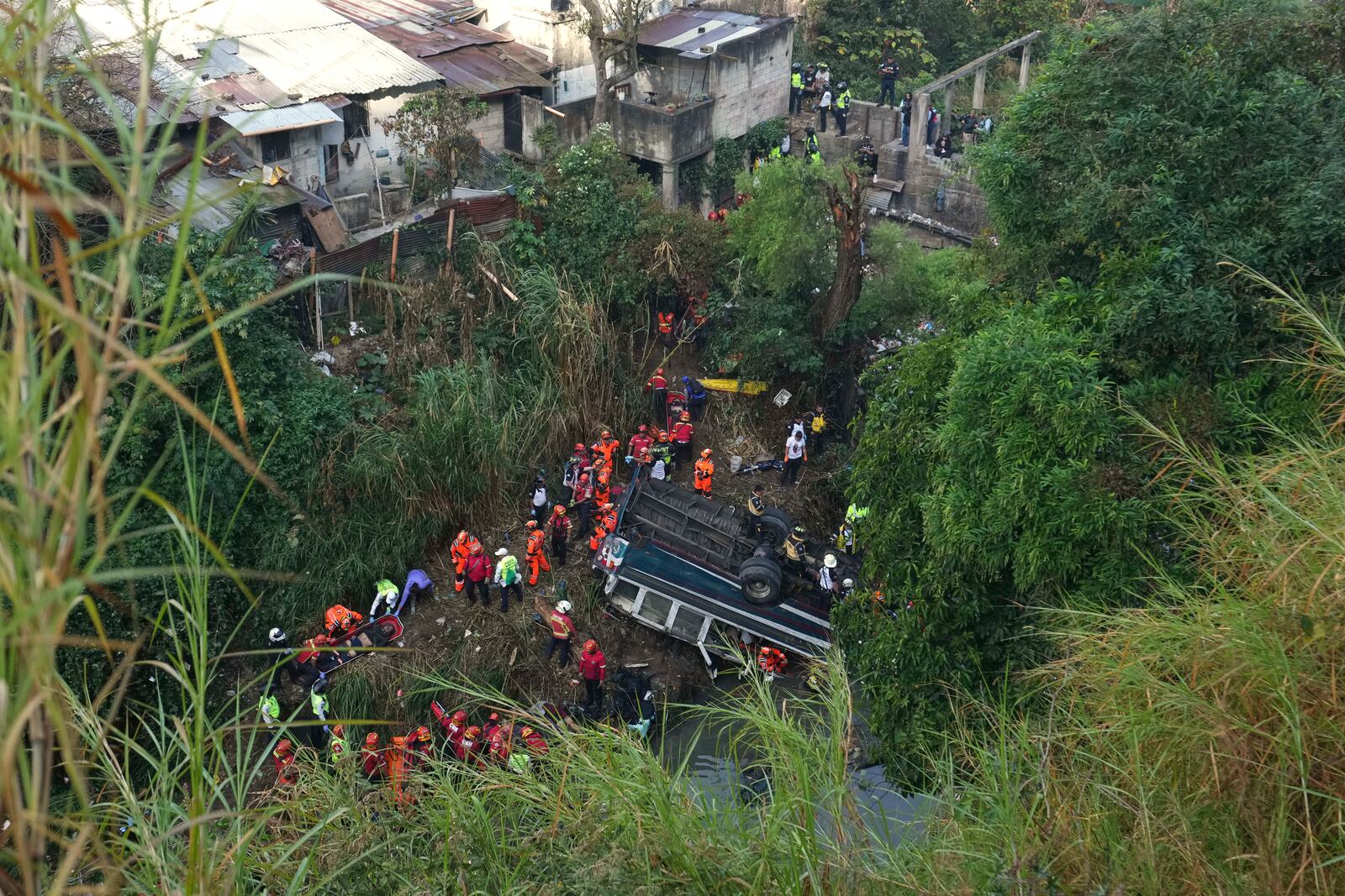 Firefighters work the scene of a fatal bus crash after it fell from a bridge on the outskirts of Guatemala City, Monday, Feb. 10, 2025. (AP Photo/Moises Castillo)