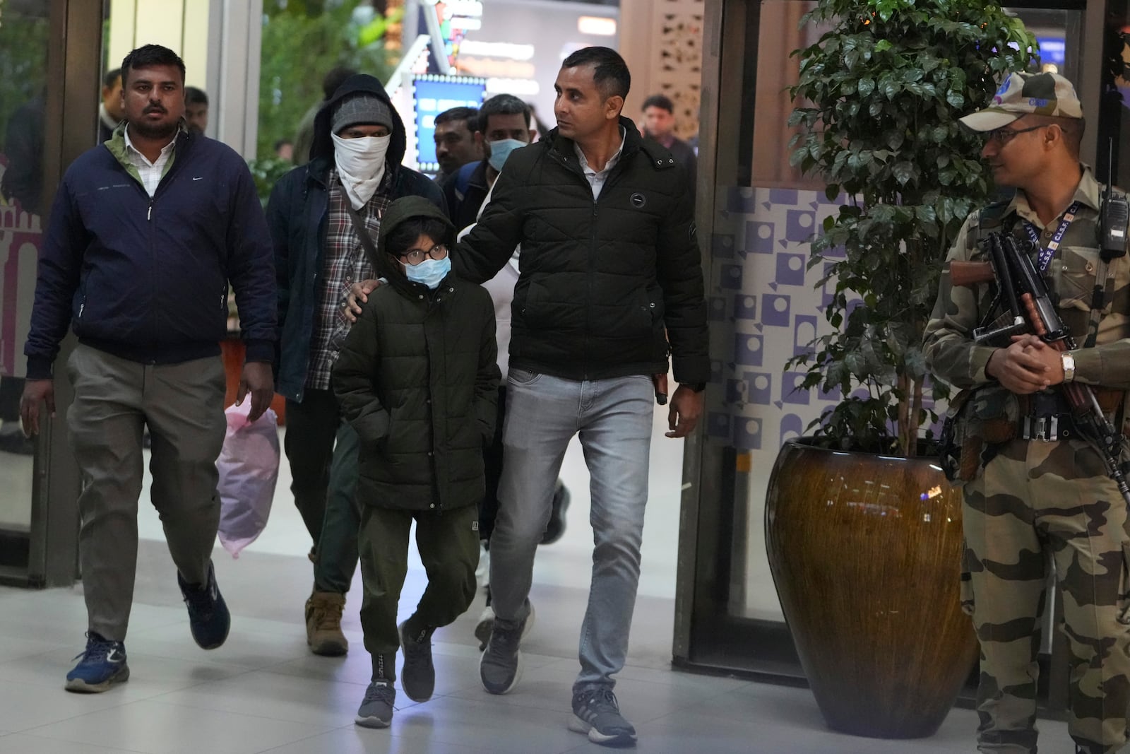 Indian police officials escort immigrants, wearing mask, deported from the United States, who were among those who arrived in a U.S. military plane the previous day in Amritsar, upon their arrival at the Ahmedabad airport in India, Feb. 6, 2025. (AP Photo/Ajit Solanki, File)