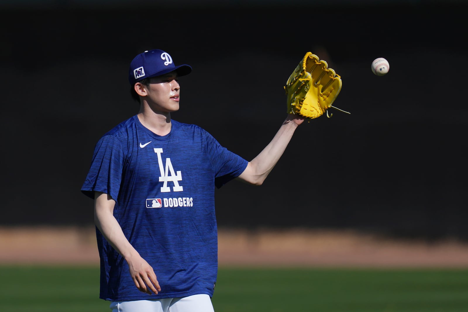 Los Angeles Dodgers pitcher Roki Sasaki, of Japan, reaches out to catch a ball as he warms up at the Dodgers baseball spring training facility Tuesday, Feb. 11, 2025, in Phoenix. (AP Photo/Ross D. Franklin)