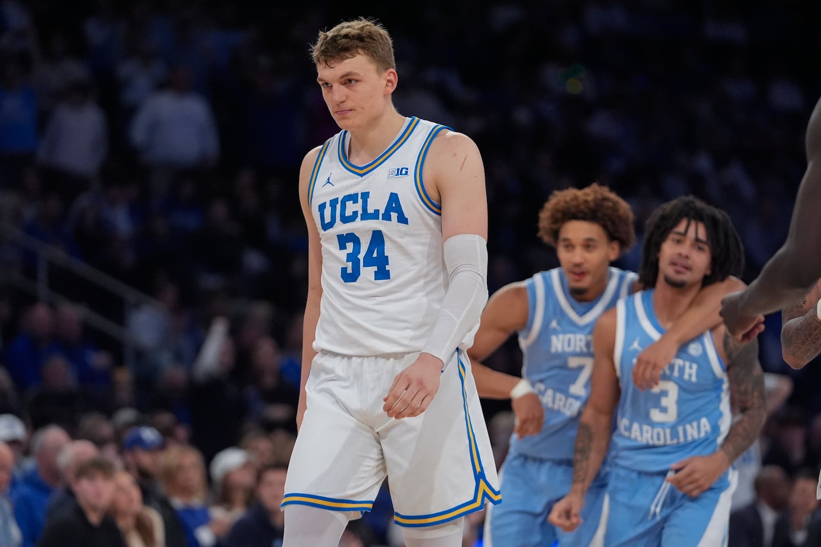 UCLA's Tyler Bilodeau (34) reacts as North Carolina's Seth Trimble (7) and Elliot Cadeau (3) celebrates during the second half of an NCAA college basketball game in the CBS Sports Classic, Saturday, Dec. 21, 2024, in New York. (AP Photo/Frank Franklin II)