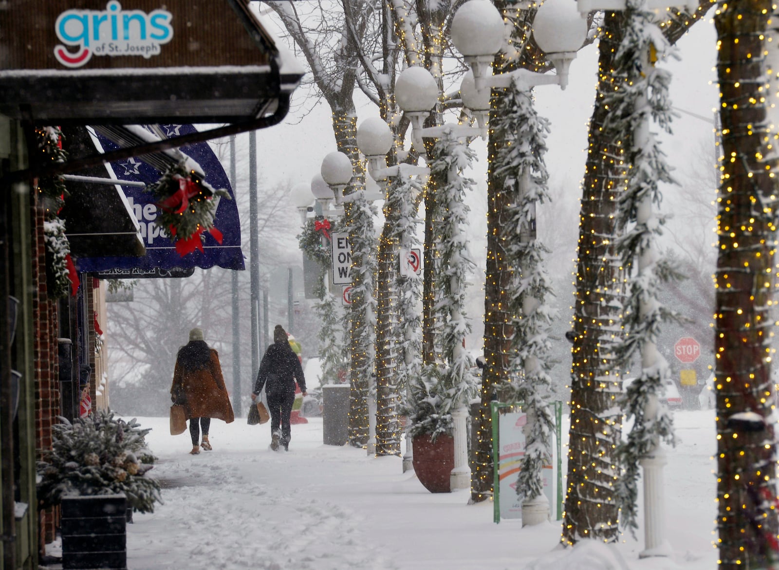 Shoppers walk through blowing and drifting snow, Monday, Dec. 2, 2024, in downtown St. Joseph, Mich. (Don Campbell/The Herald-Palladium via AP)