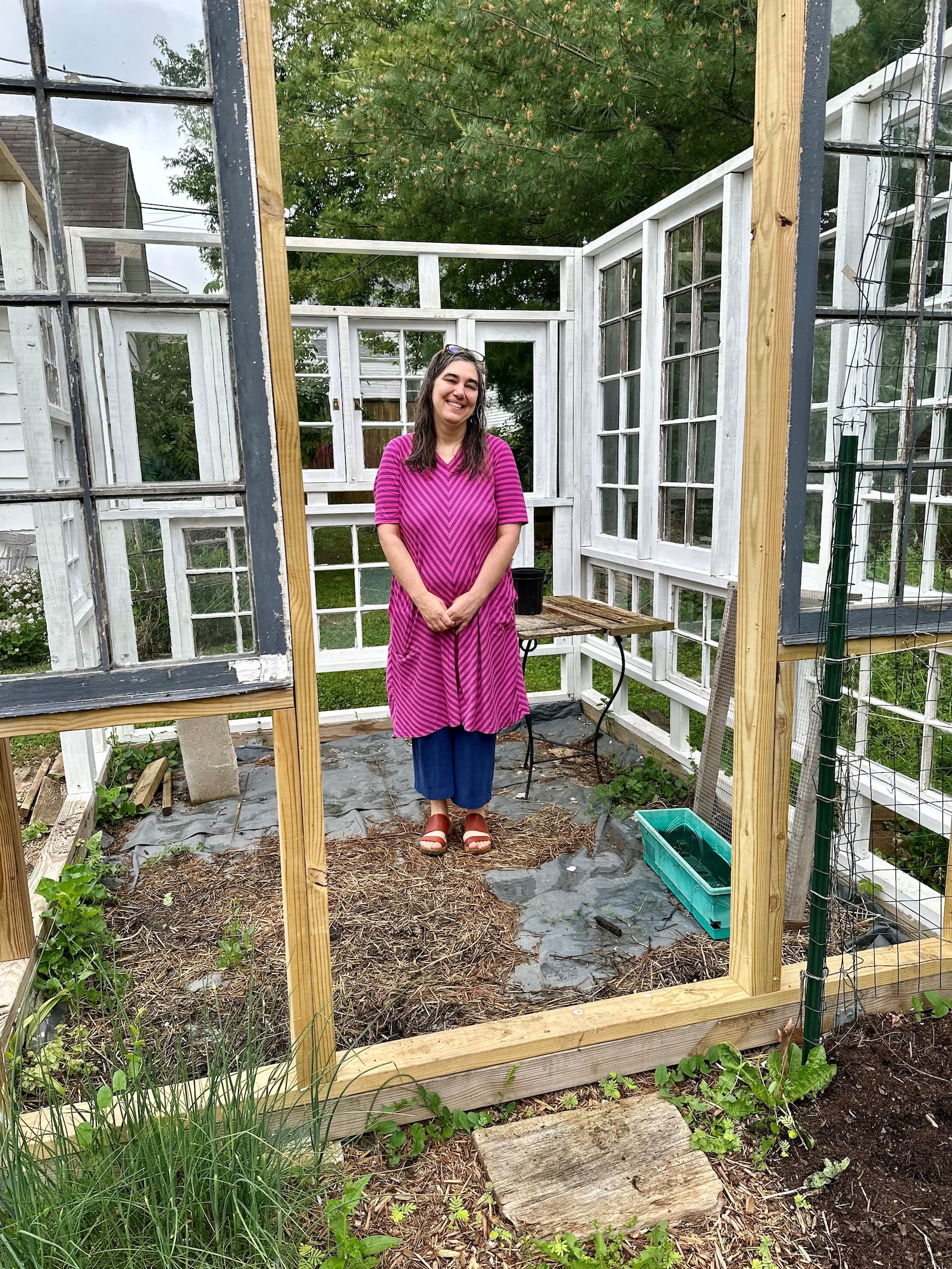 Kathleen Tandy stands inside the greenhouse she is building with old windows. ROBIN McMACKEN/STAFF 