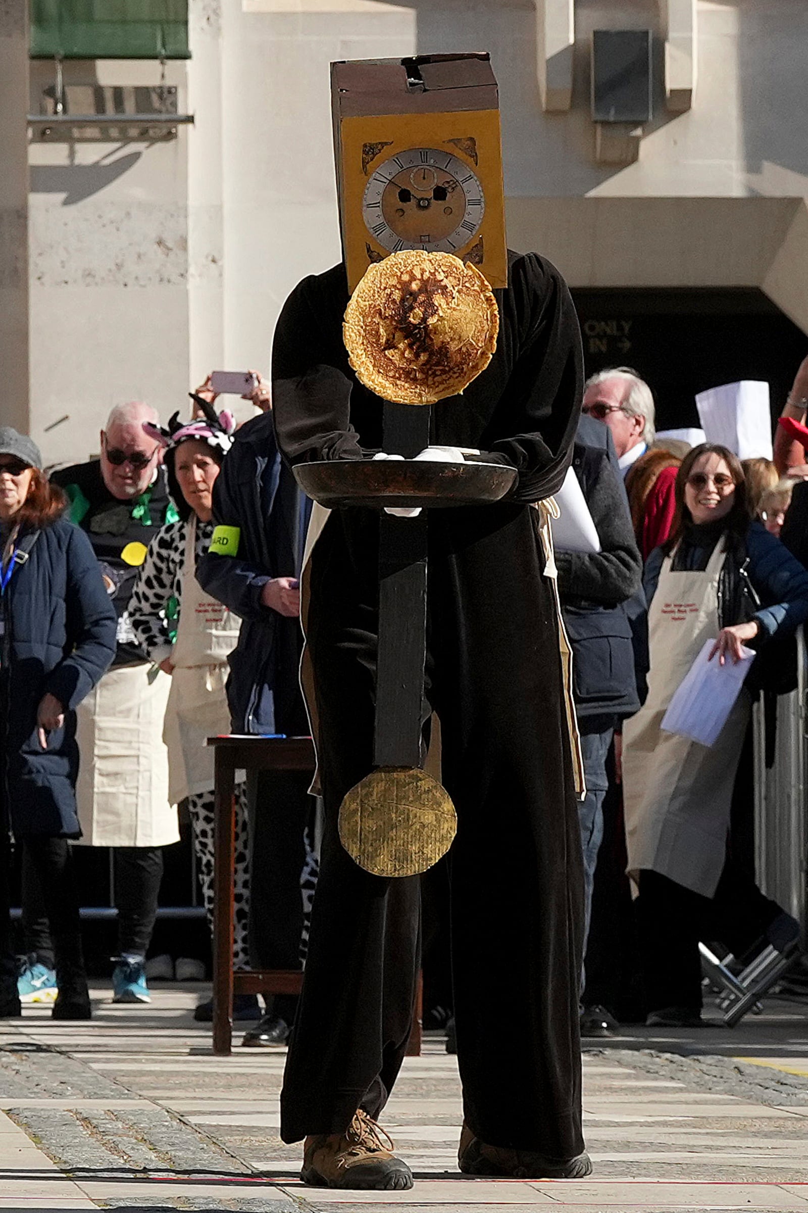 A competitor in a costume flips a pancake during a traditional pancake race by livery companies at the Guildhall in London, Tuesday, March 4, 2025.(AP Photo/Frank Augstein)