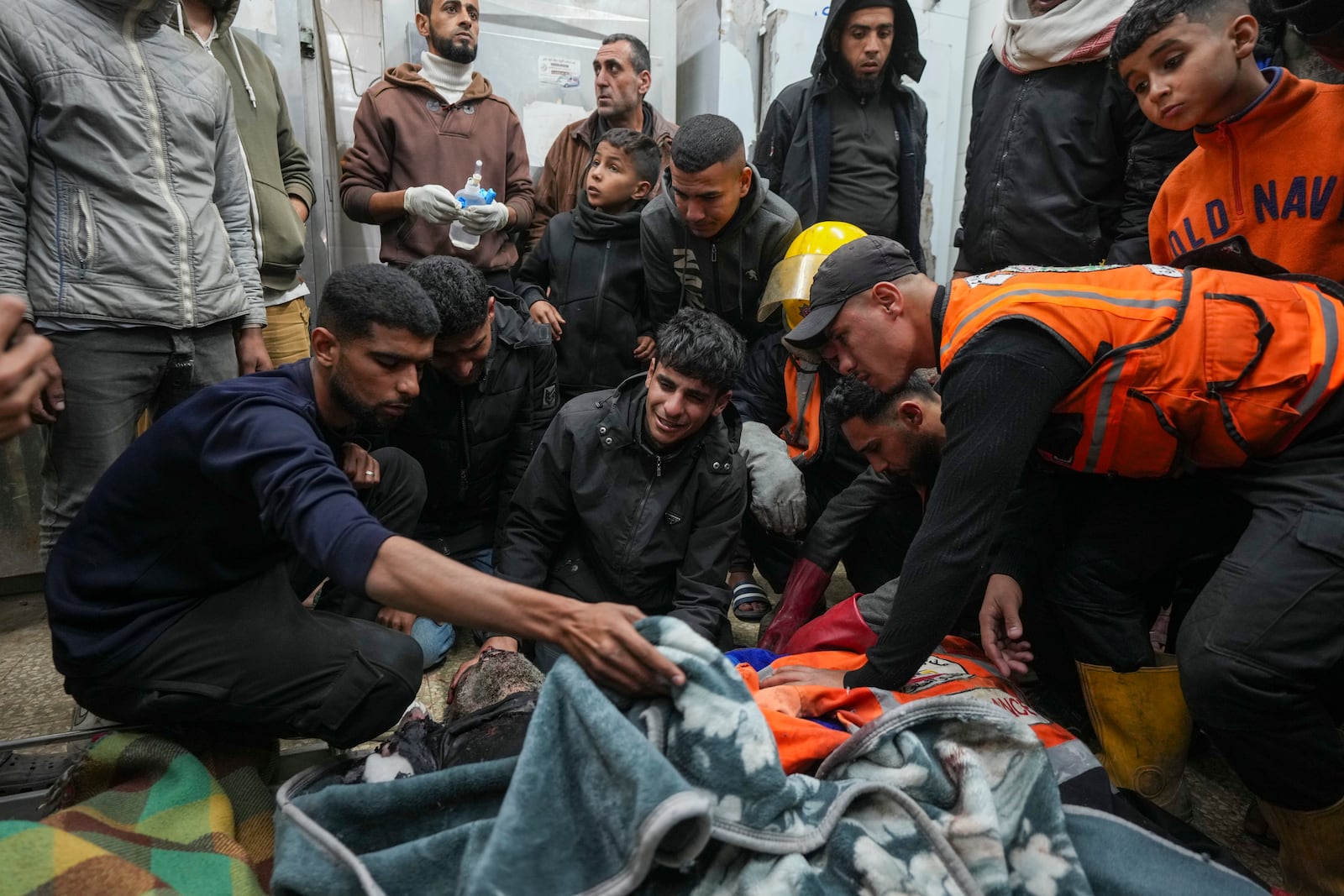 Palestinians mourn over the bodies of civil defense workers victims of an Israeli army strike in the Nuseirat camp, at the Al-Aqsa Martyrs hospital in Deir al-Balah, central Gaza Strip, Sunday Dec.16, 2024. Four cicivil defence workers were killed according to Palestinian civil defense and health ministry.(AP Photo/Abdel Kareem Hana)