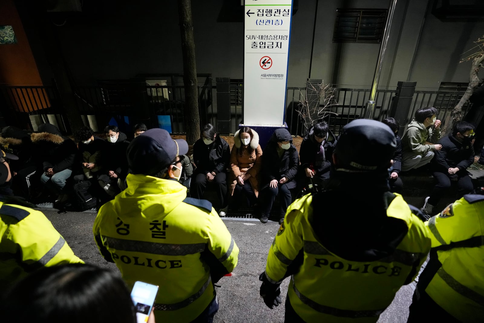 Police officers stand in front of supporters of impeached South Korean President Yoon Suk Yeol after they illegally climbed over a fence inside the Seoul Western District Court in Seoul, South Korea, Saturday, Jan. 18, 2025. (AP Photo/Ahn Young-joon)