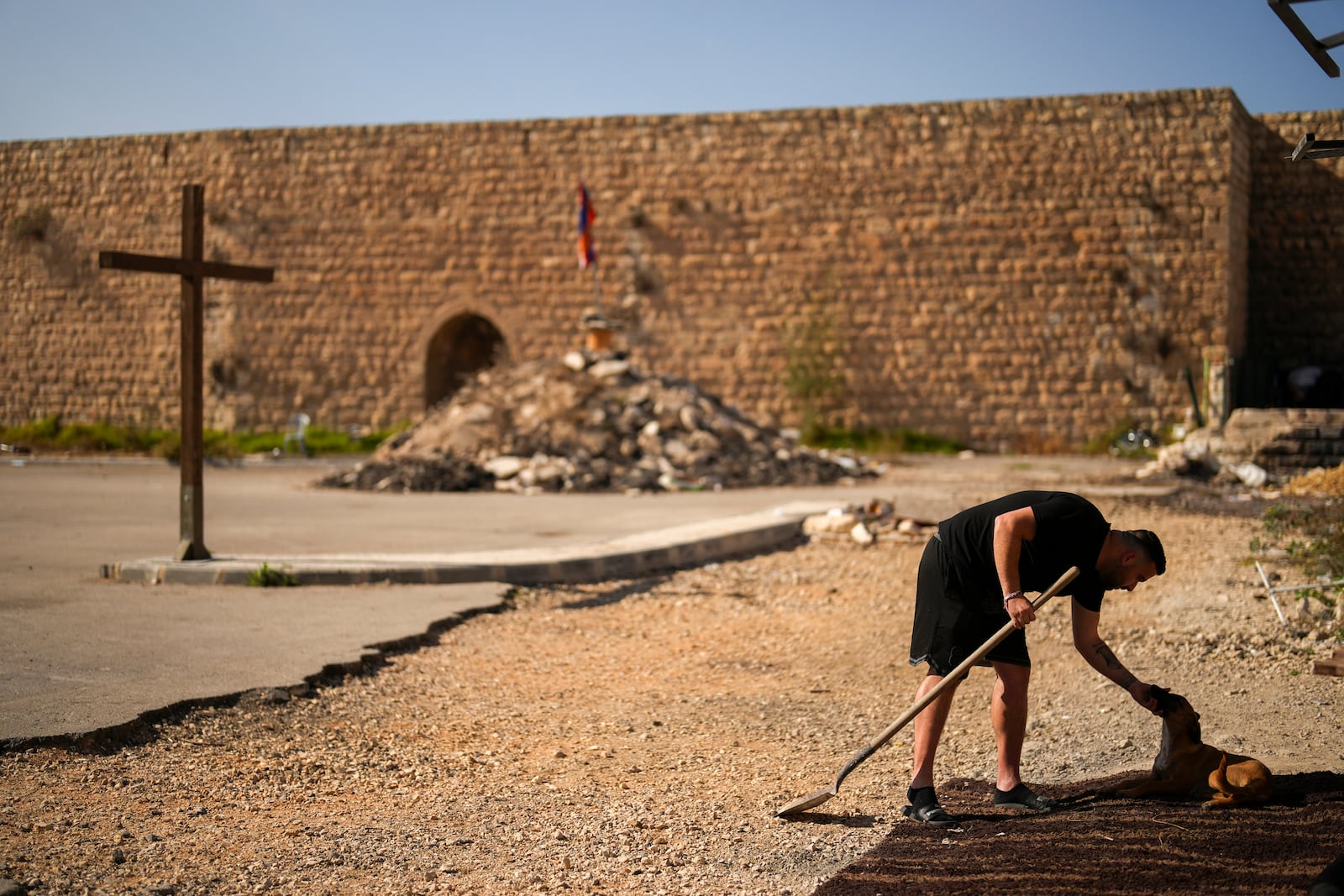 An Armenian activist pets a dog in a parking area known by locals as "Cows garden" at the Armenian quarter in Jerusalem, Thursday, Nov. 21, 2024. (AP Photo/Francisco Seco)