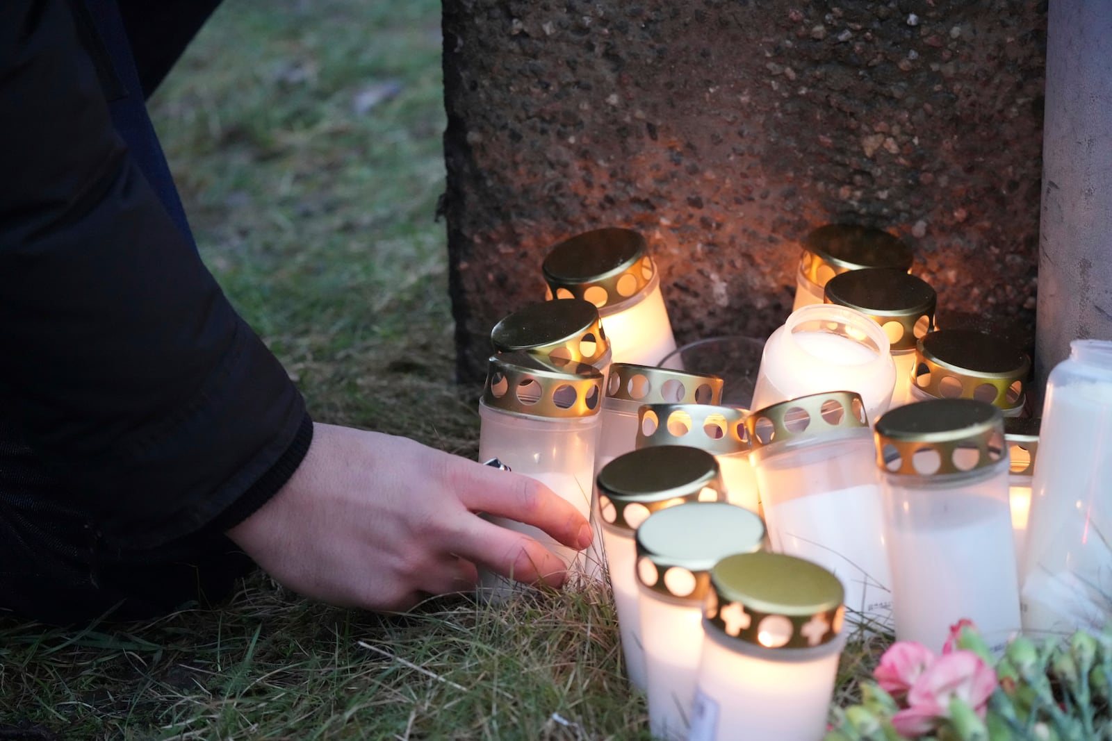 A man lights a candle at a makeshift memorial near the scene of a shooting at an adult education center on the outskirts of Orebro, Sweden, Wednesday, Feb. 5, 2025. (AP Photo/Sergei Grits)