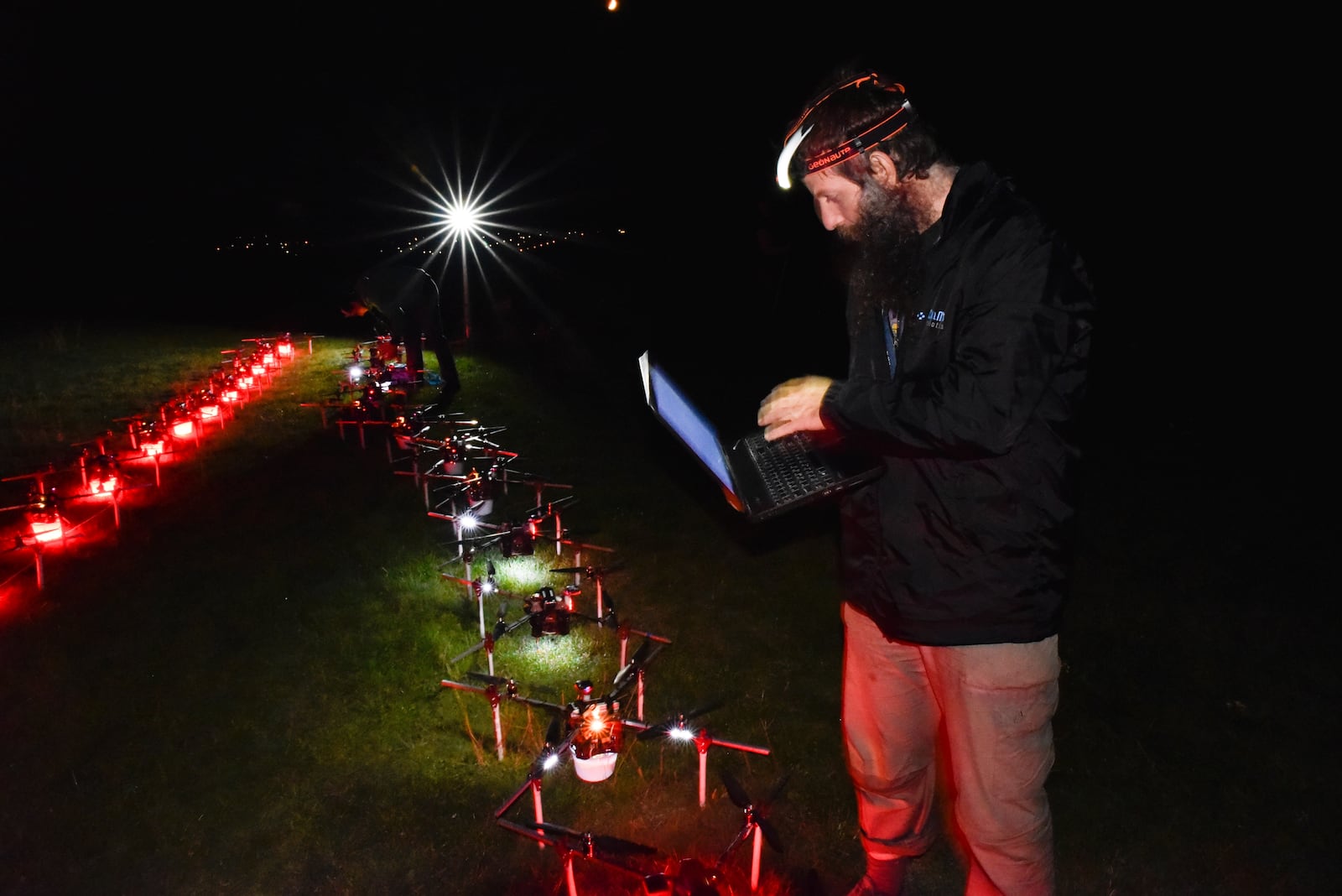 In this handout photo Gabor Vasarhelyi, physicist and researcher of the Department of Biological Physics at Eötvös Loránd University, is using his computer to set a swarm of 100 quadcopters to fly autonomously during an experiment near Budapest, Hungary, Thursday, Oct. 21, 2021. (AP Photo/HO/Eotvos Lorand University)