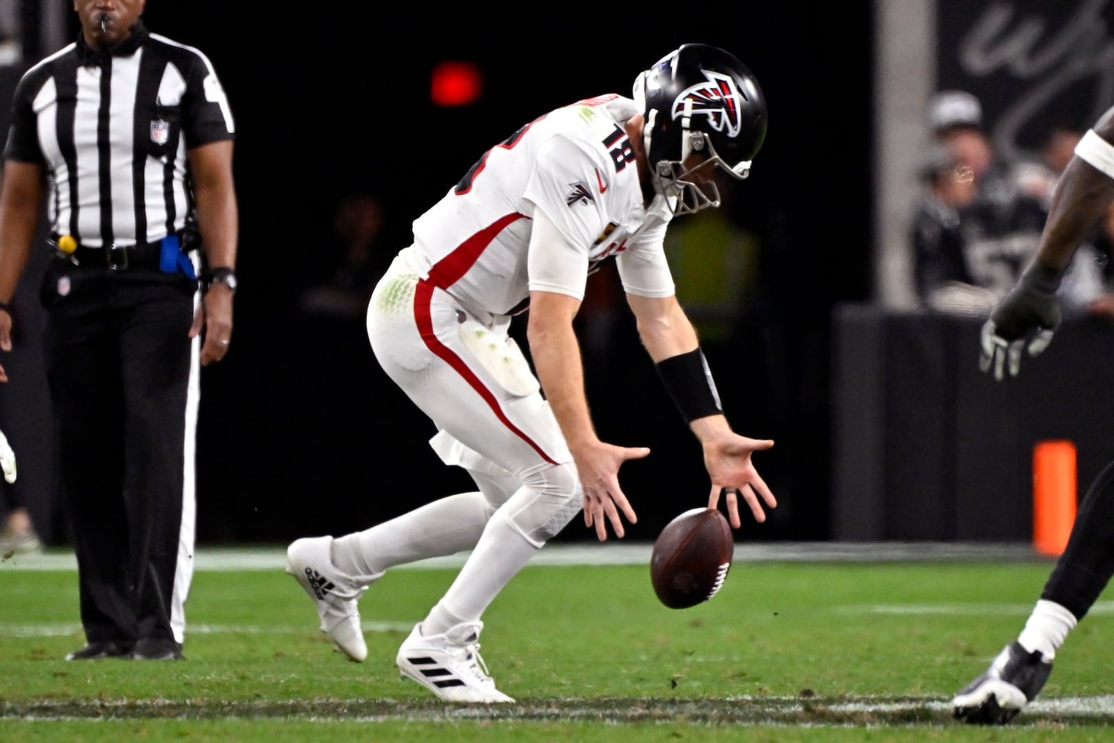 Atlanta Falcons quarterback Kirk Cousins recovers a bad snap during the second half of an NFL football game against the Las Vegas Raiders, Monday, Dec. 16, 2024, in Las Vegas. (AP Photo/David Becker)