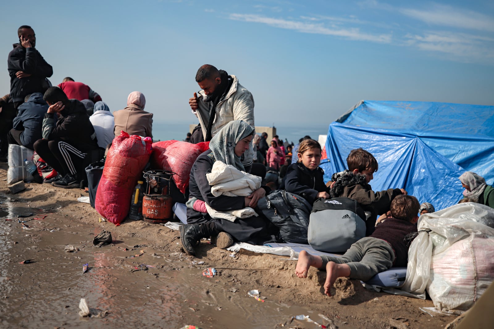 Displaced Palestinians gather with their belongings near a roadblock on the al Rashid Street, as they wait to return to their homes in the northern part of the Gaza Strip, Sunday, Jan. 26, 2025, days after the ceasefire deal between Israel and Hamas came into effect. (AP Photo/ Jehad Alshrafi)