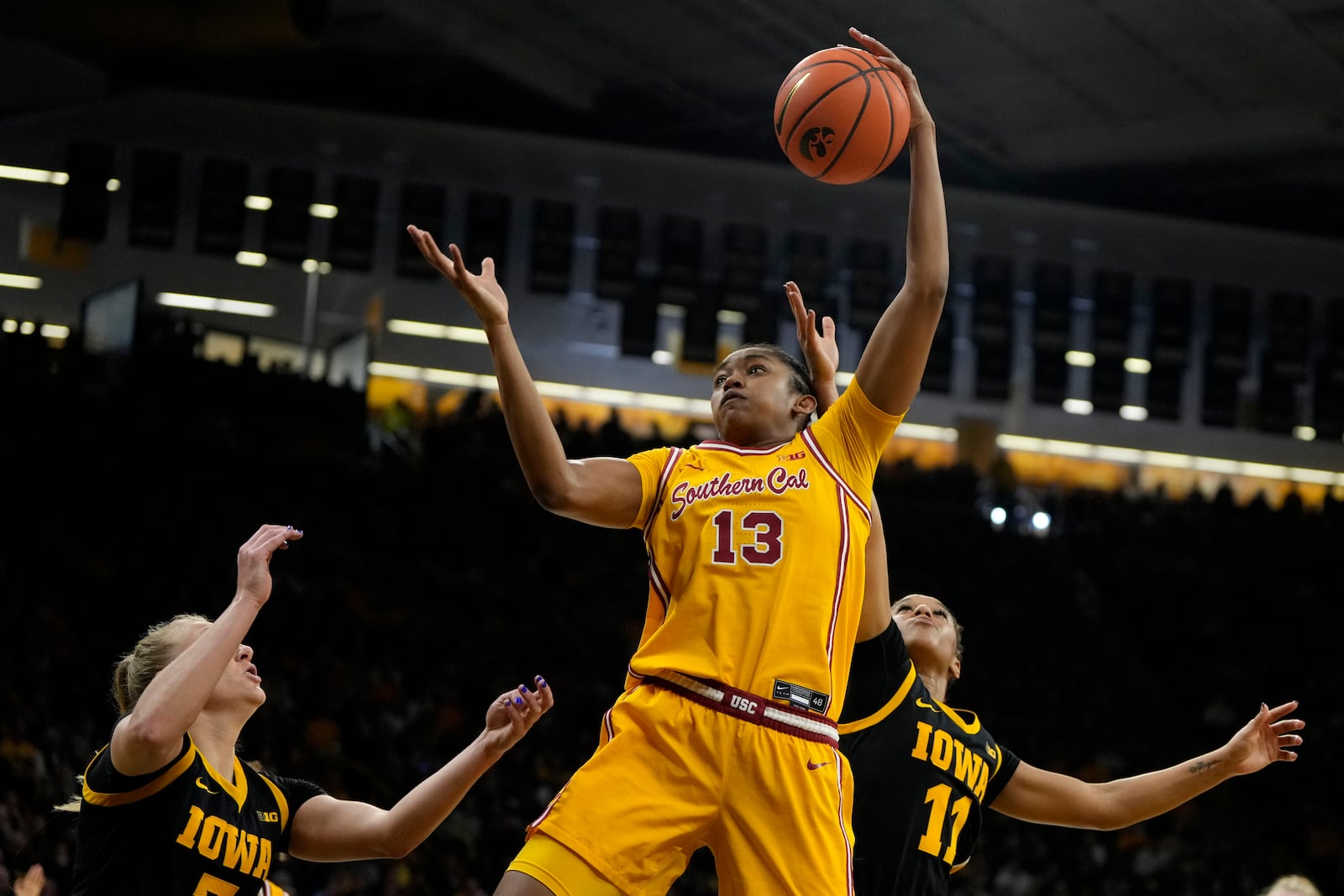 Southern Cal center Rayah Marshall (13) grabs a rebound over Iowa guards Sydney Affolter, left, and Aaliyah Guyton, right, during the first half of an NCAA college basketball game, Sunday, Feb. 2, 2025, in Iowa City, Iowa. (AP Photo/Charlie Neibergall)