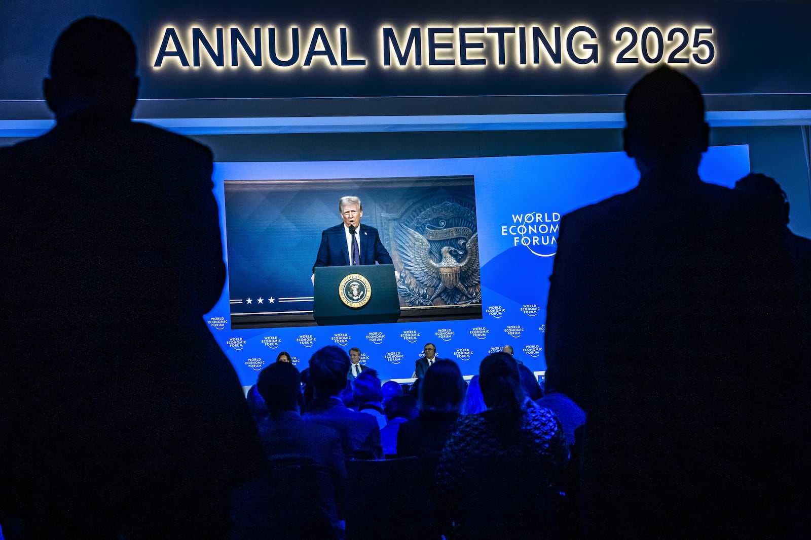 US President Donald J. Trump is shown on screens as he addresses via remote connection a plenary session in the Congress Hall, during the 55th annual meeting of the World Economic Forum (WEF), in Davos, Switzerland, Thursday, Jan. 23, 2025. (Michael Buholzer/Keystone via AP)