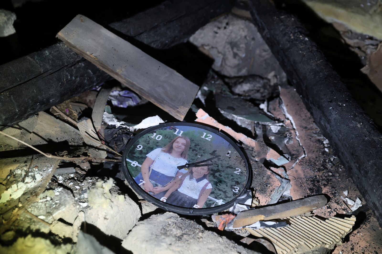 A clock with a family photo is seen among debris of a residential house destroyed by a Russian drone strike in Zaporizhzhia, Ukraine, Friday, March 21, 2024. (AP Photo/Kateryna Klochko)