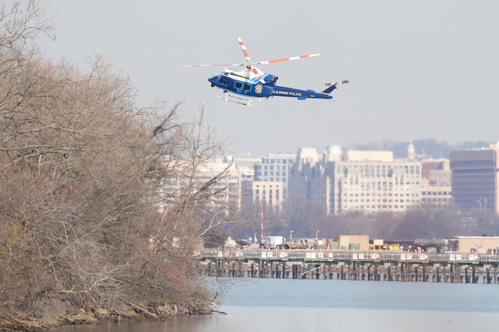 US Park Police helicopter during search and rescue efforts around a wreckage site in the Potomac River from Ronald Reagan Washington National Airport, early Thursday morning, Jan. 30, 2025, in Arlington, Va. (AP Photo/Carolyn Kaster)