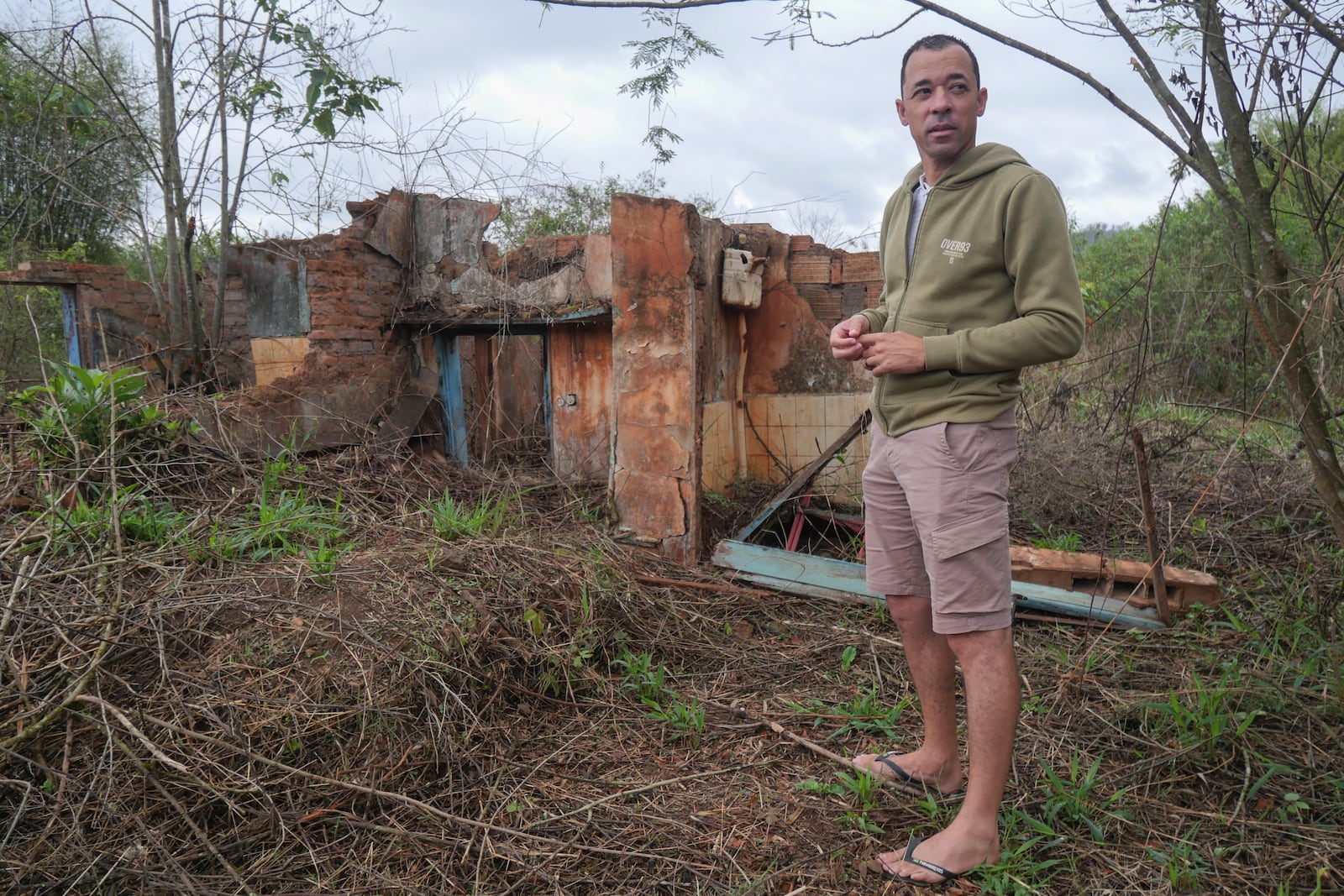 Cristiano Sales stands in front of the ruins of his house washed over by sludge in a 2015 collapse of a dam owned by the mining company Samarco, a joint venture of Brazilian mining operation Vale and Anglo-Australian firm BHP, in Bento Rodrigues, Minas Gerais state, Brazil, Oct. 19, 2024. (AP Photo/Eleonore Hughes)