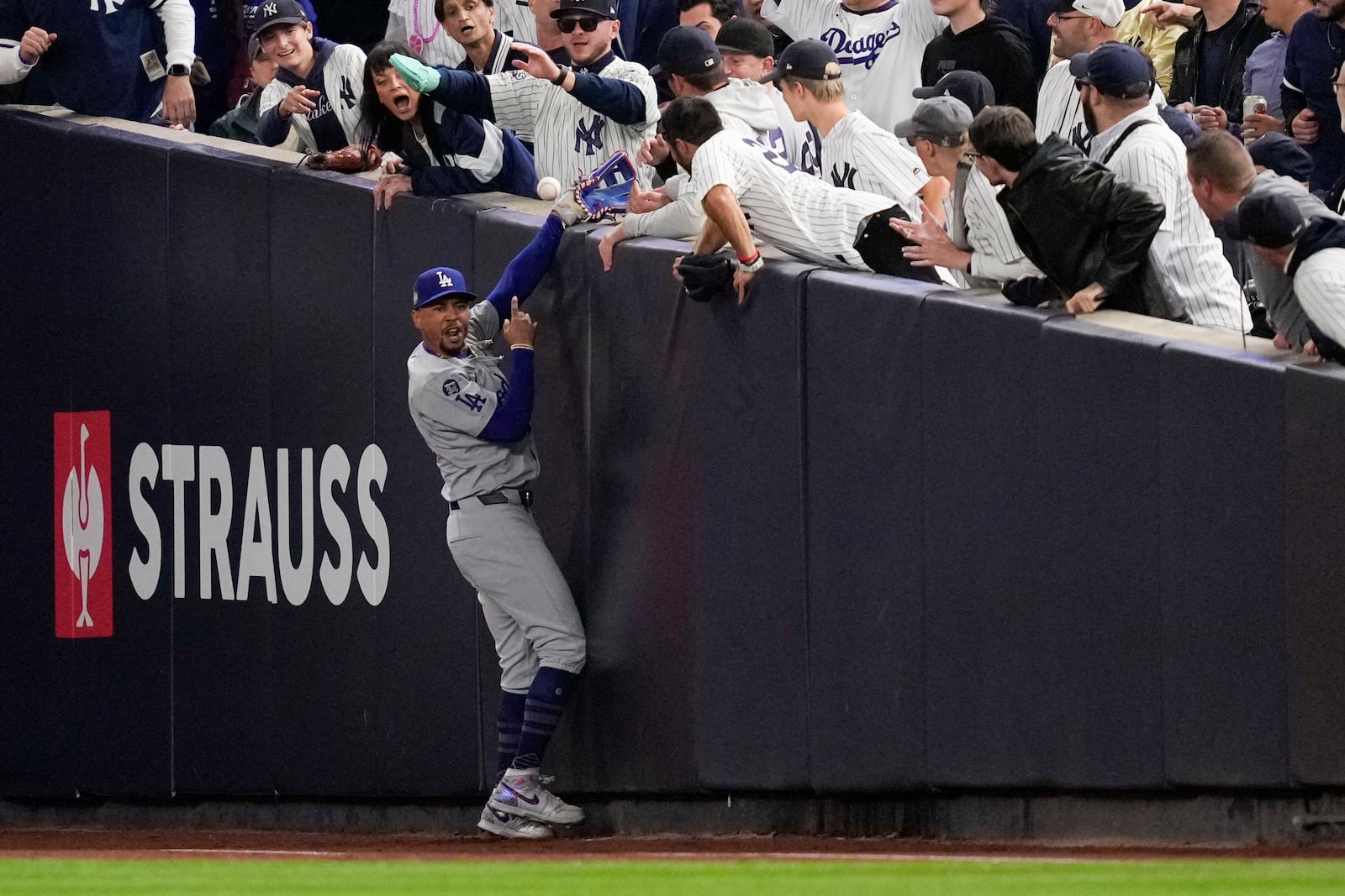 Fans interfere with a foul ball caught by Los Angeles Dodgers right fielder Mookie Betts during the first inning in Game 4 of the baseball World Series against the New York Yankees, Tuesday, Oct. 29, 2024, in New York. (AP Photo/Ashley Landis)