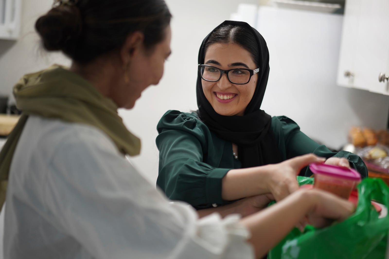 Maryam Rahimi, left, and Marjila Badakhsh prepare food for a neighbor and fellow Afghan refugee at their apartment in Alexandria, Va., Wednesday, March 5, 2025. (AP Photo/Jessie Wardarski)