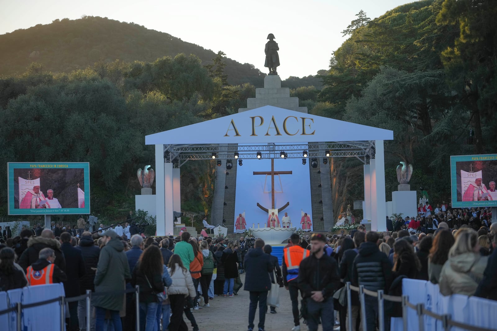 The statue of Napoleon towers Ajaccio "Place d'Austerlitz" as Pope Francis presides over a mass during his visit in the French island of Corsica, Sunday, Dec. 15, 2024. The writing on top of the altar reads: Peace. (AP Photo/Alessandra Tarantino)