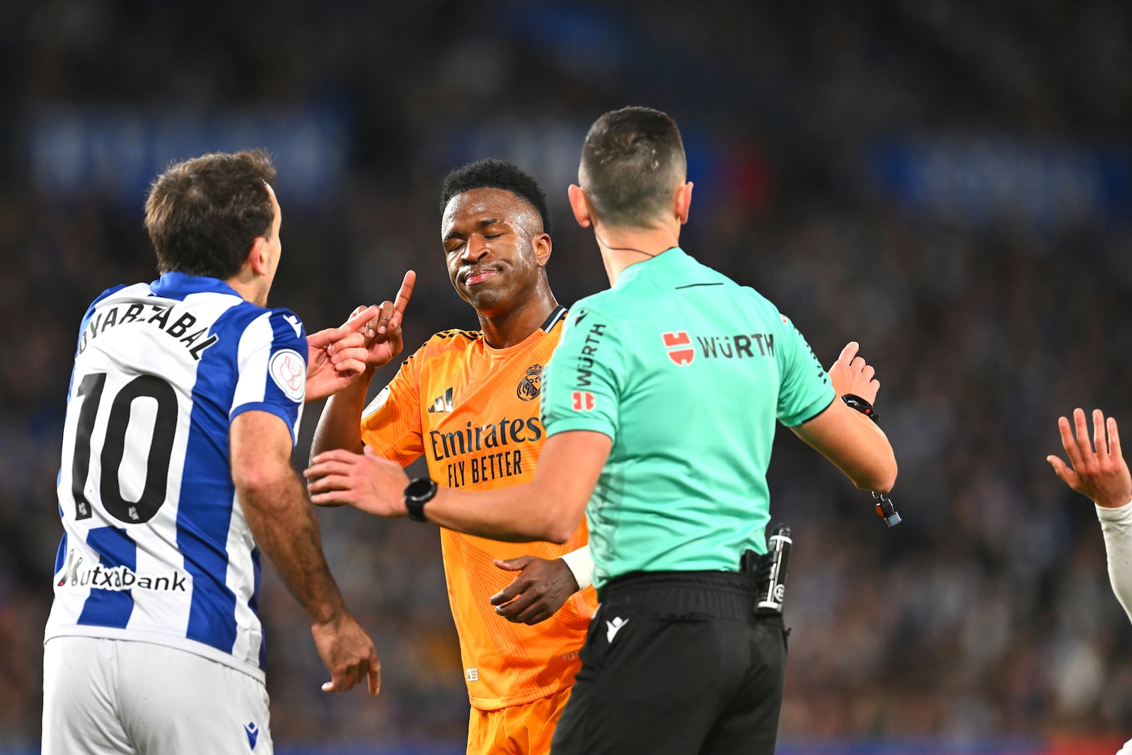 Real Sociedad's Mikel Oyarzabal, left, argues with Real Madrid's Vinicius Junior, centre, during the Spanish Copa del Rey soccer match between Real Sociedad and Real Madrid at the Reale Arena in San Sebastian, Spain, Wednesday, Feb. 26, 2025. (AP Photo/Miguel Oses)